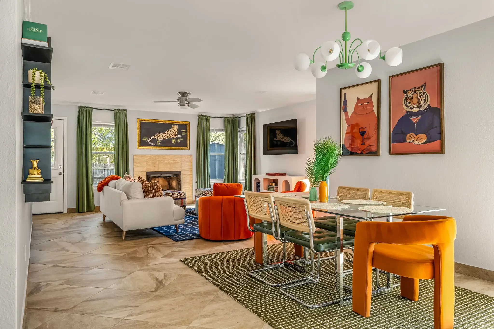 Airbnb open plan living and dining design with bold animal art, orange seating, fireplace, and green curtains — Austin TX.