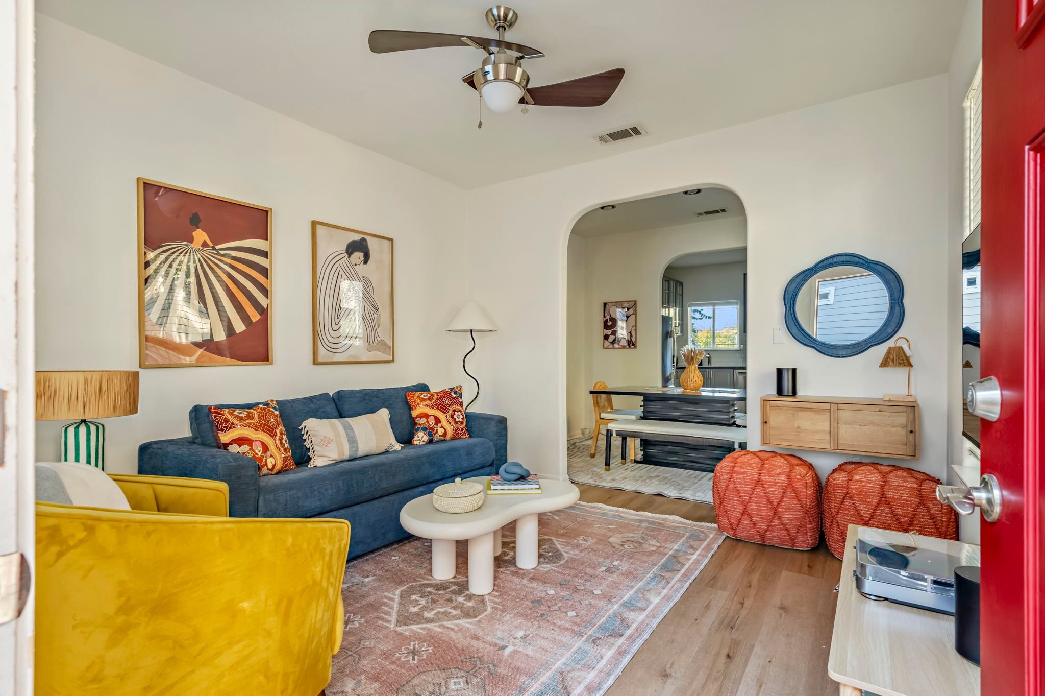 Boho living room styled for short-term rental, with blue pull-out sofa, western rug, arched doorways, and colorful decor.