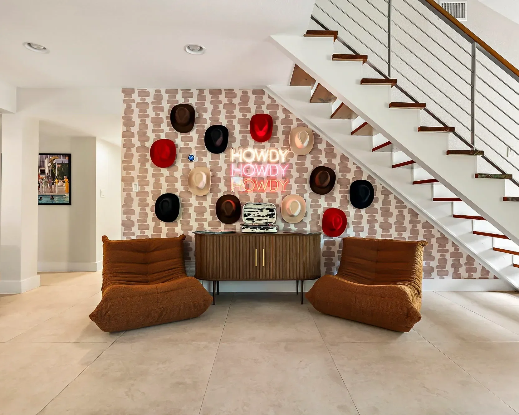 Desert Disco short-term rental design project — eclectic lounge with cowboy hat wall display, Howdy neon signs, and togo chairs.