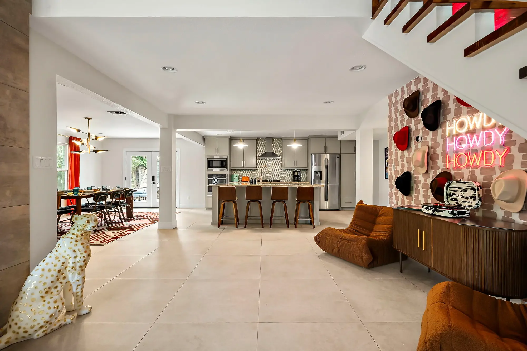 Airbnb open plan design with cowboy hat wall, Howdy neon sign, dalmatian statue, and view to dining and kitchen — Austin TX.