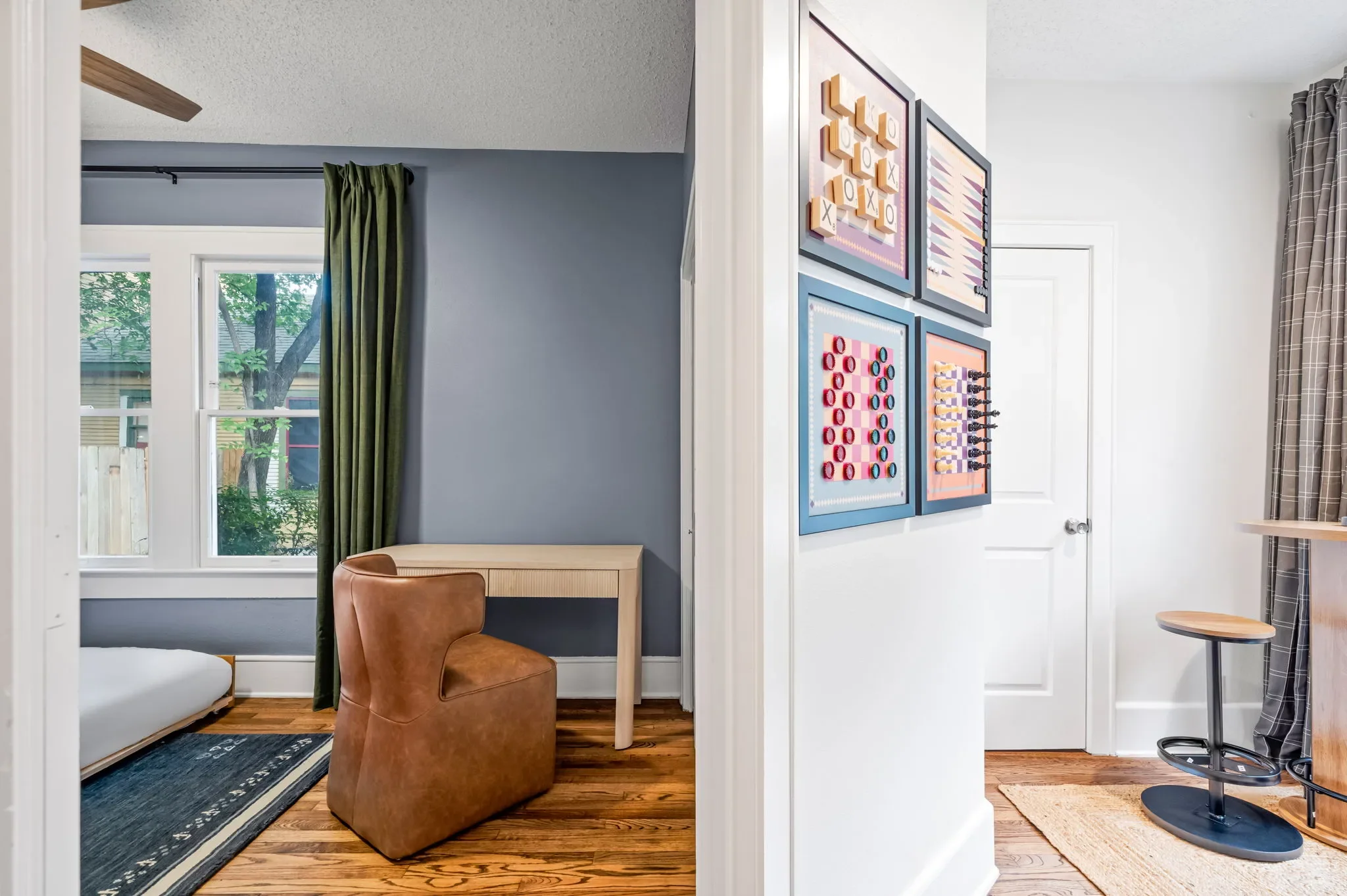 Airbnb bunk room design detail with framed board game art gallery wall, leather bean bag, and bar height side table — Austin TX.