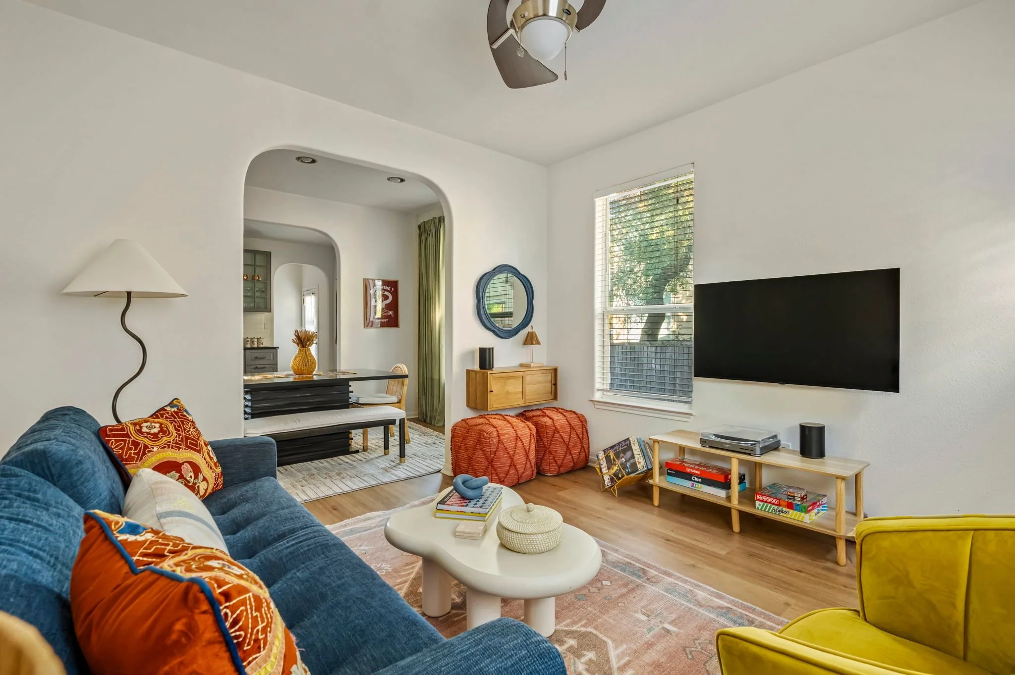 Eclectic living room with blue pull-out sofa and arched walkways leading to the dining area.