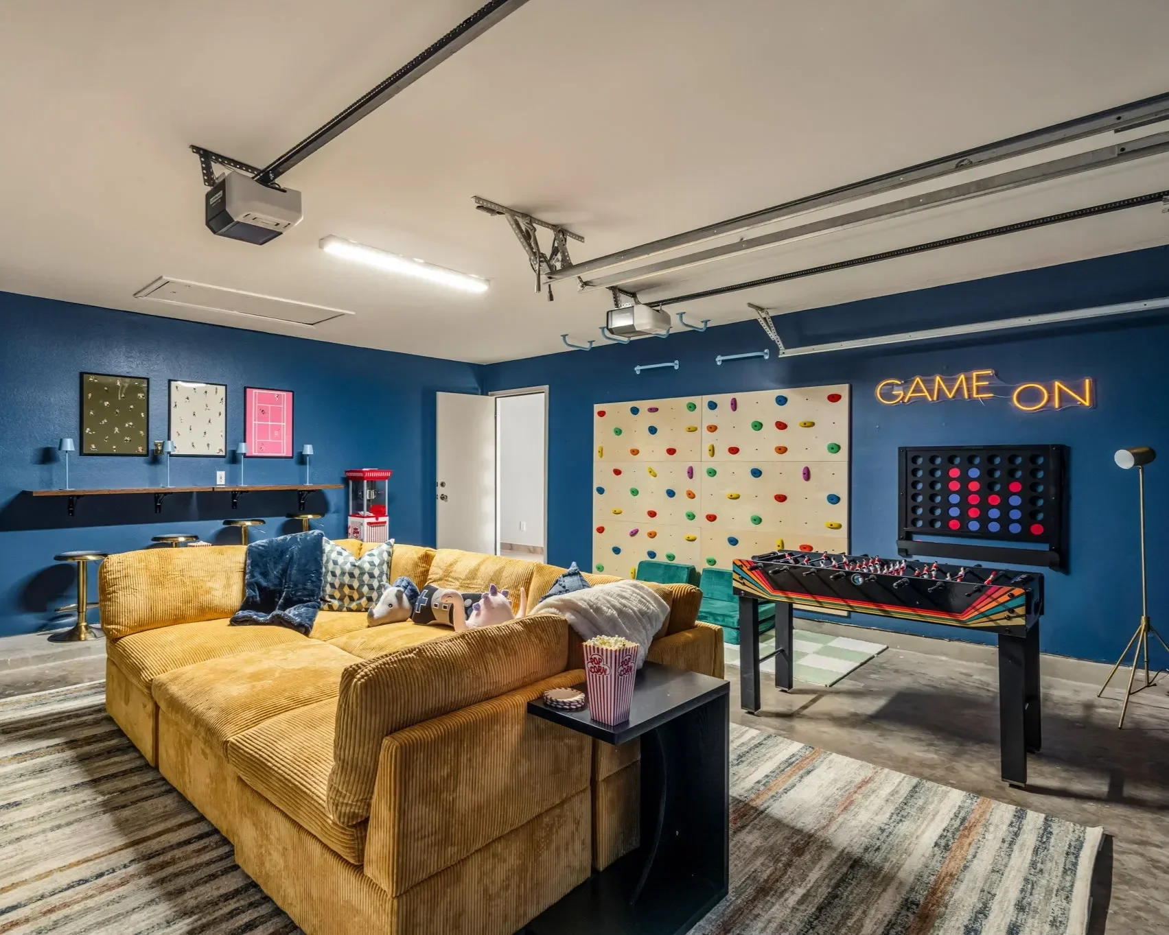 Entertainment-focused game room with sectional seating, foosball table, climbing wall, and bold design elements for guests and families.