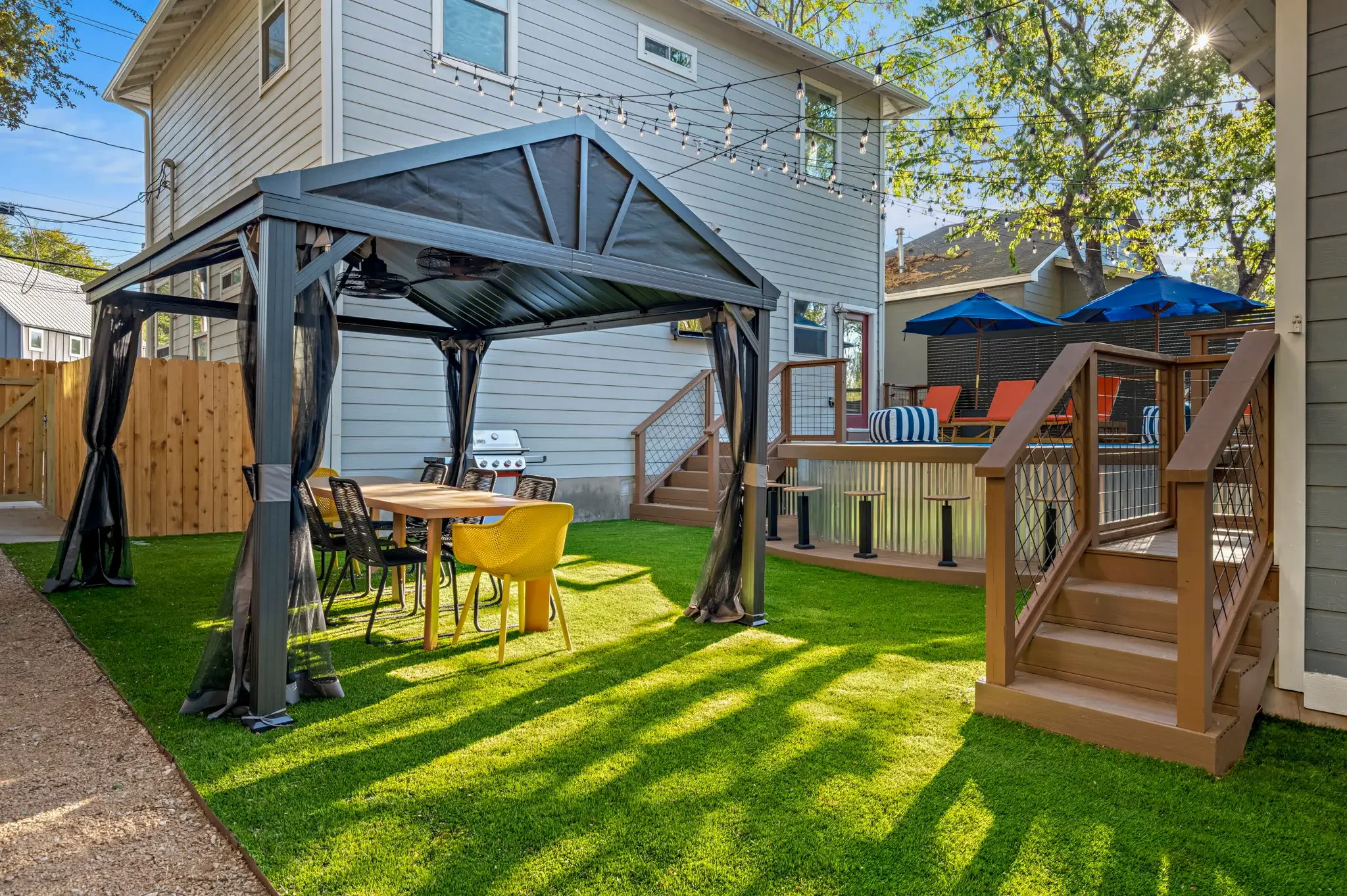 Backyard outdoor gazebo featuring dining seating, a renovated wood patio, an above-ground pool, lounge chairs, and umbrellas.