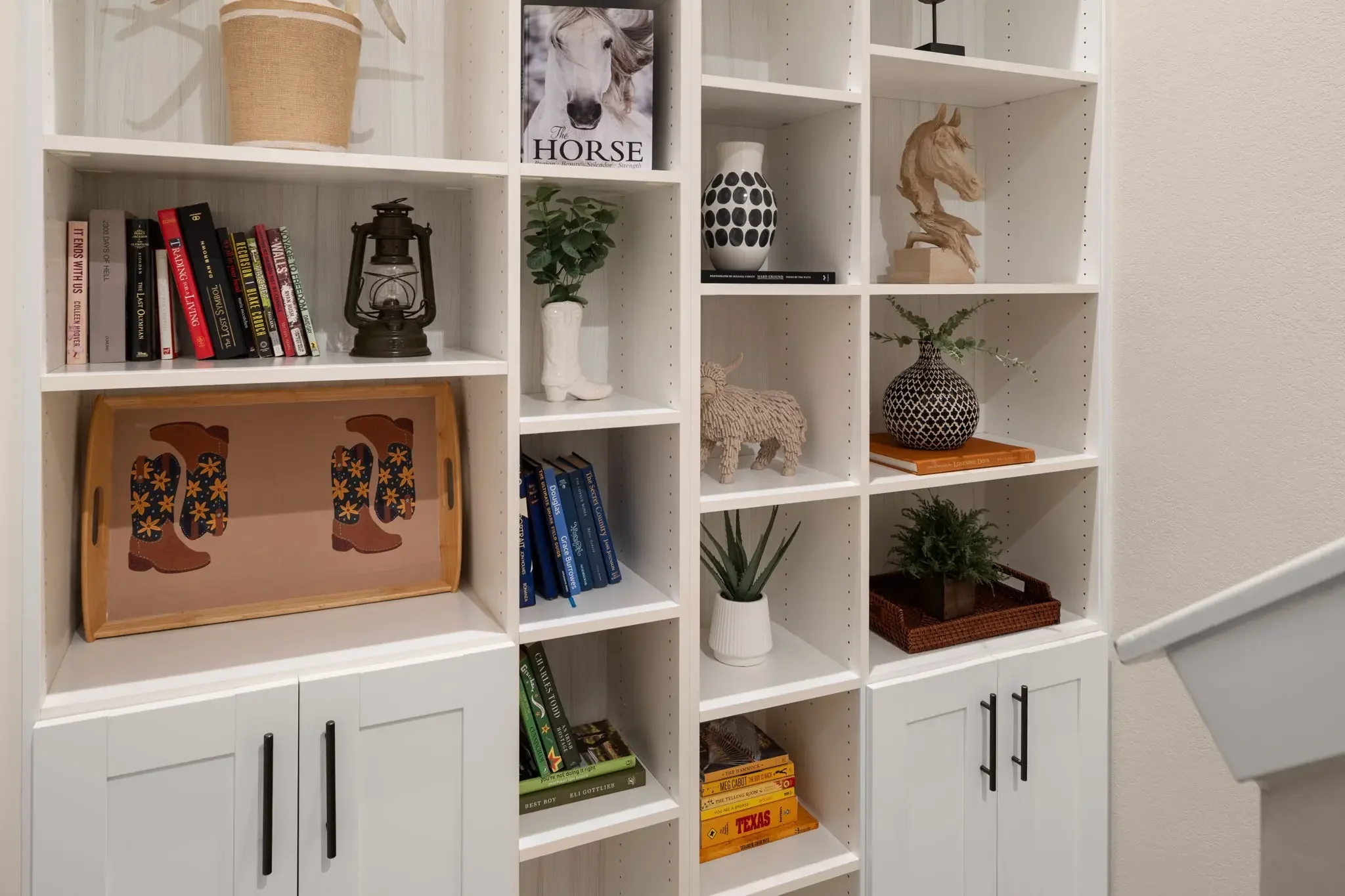 Airbnb interior design detail with styled built-in shelving, western books, cowboy boot tray, and curated decor — Austin TX.