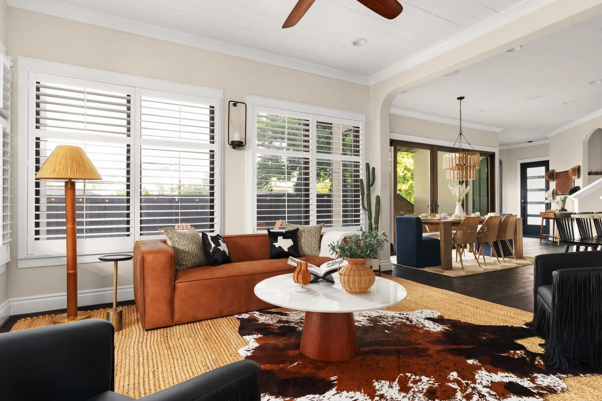 Short-term rental living room with leather sofa, cowhide rug, and open plan dining — Sunset Saloon Austin.