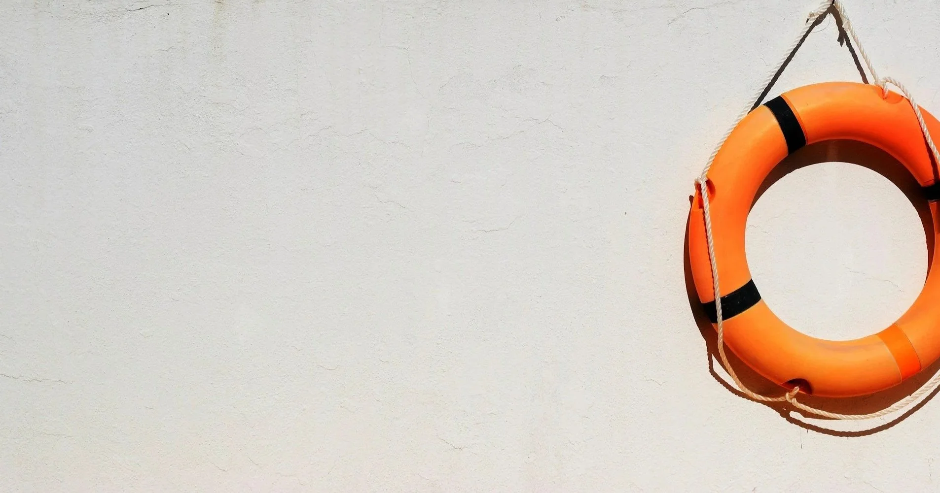 A person's hand attaching a yellow sticky note to a wall with other sticky notes arranged in a grid.