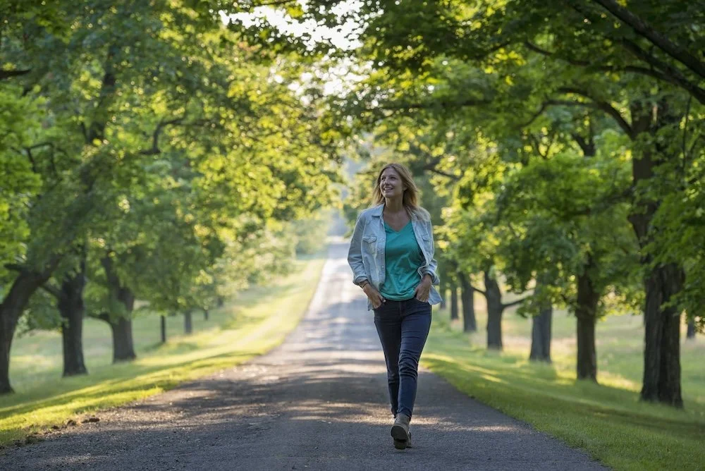 A healthy woman walking down a tree lined road in Horsham, PA.