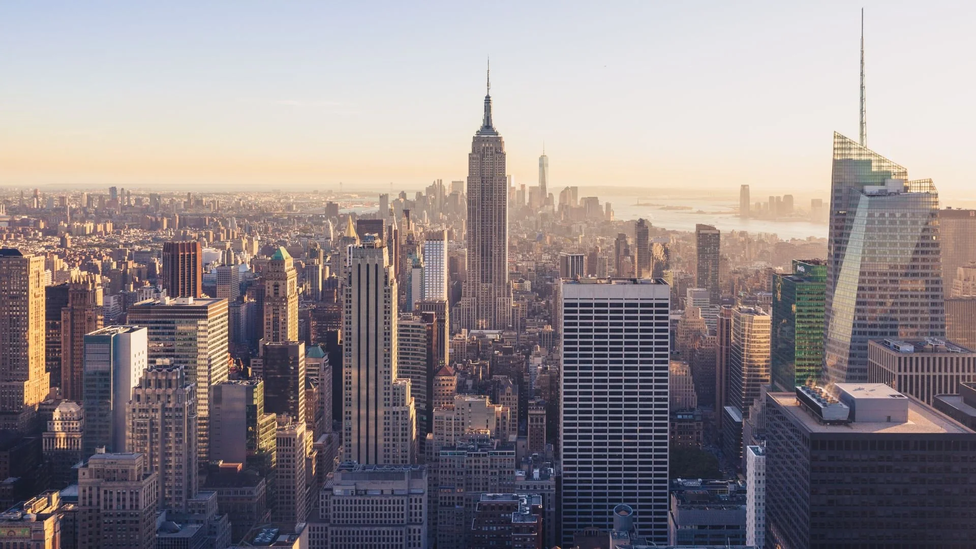 Aerial view of Manhattan skyline with the Empire State Building and other skyscrapers during sunset.
