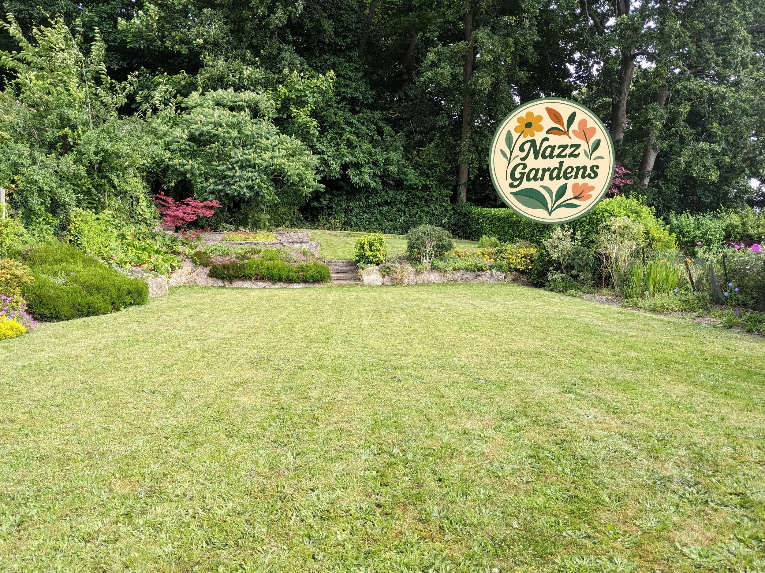 A well-maintained garden with a lush green lawn, colorful flower beds, and a large sign reading 'Nazz Gardens' amidst green trees.