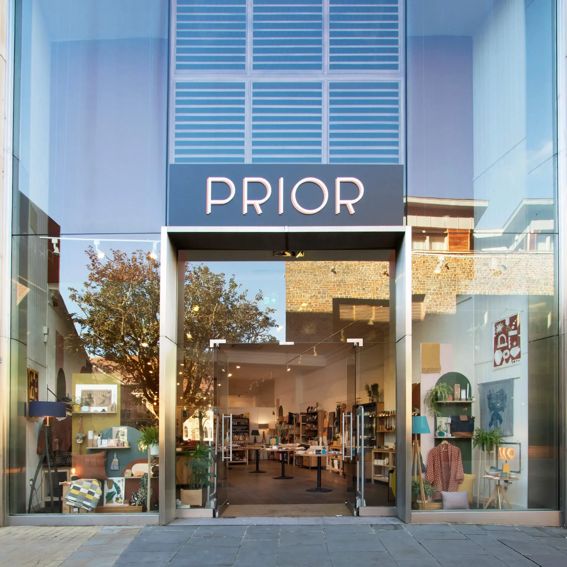 storefront with large glass windows labeled 'PRIOR', displaying home decor items, furniture, and plants inside.