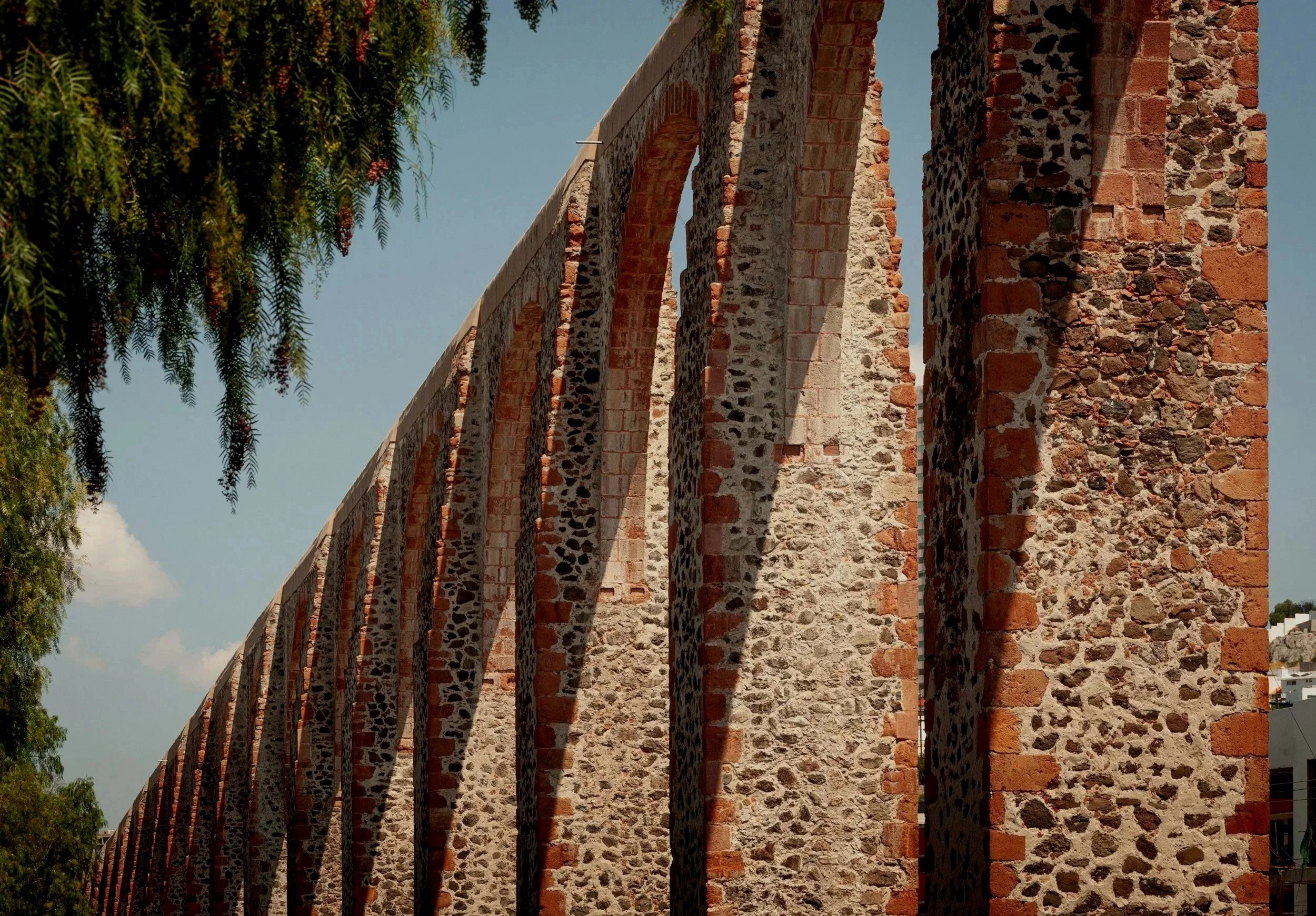 Vista de un acueducto de piedra y ladrillo, con arcos apuntados, bajo un cielo despejado.