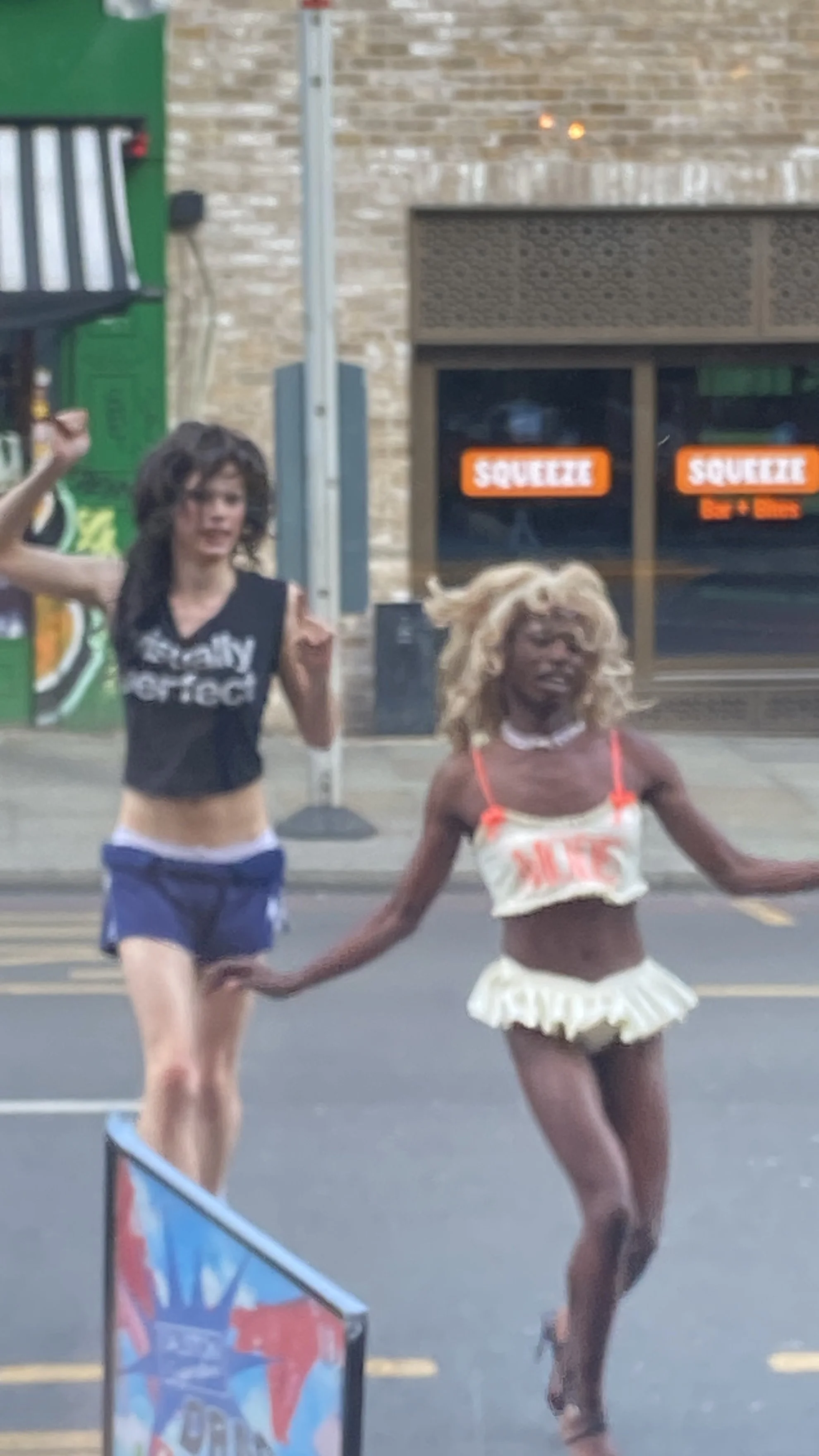 Lala Dangereuse being chased by Pina Busch at  Dalston Superstore drag brunch wearing the white and orange Mode latex ensemble. 