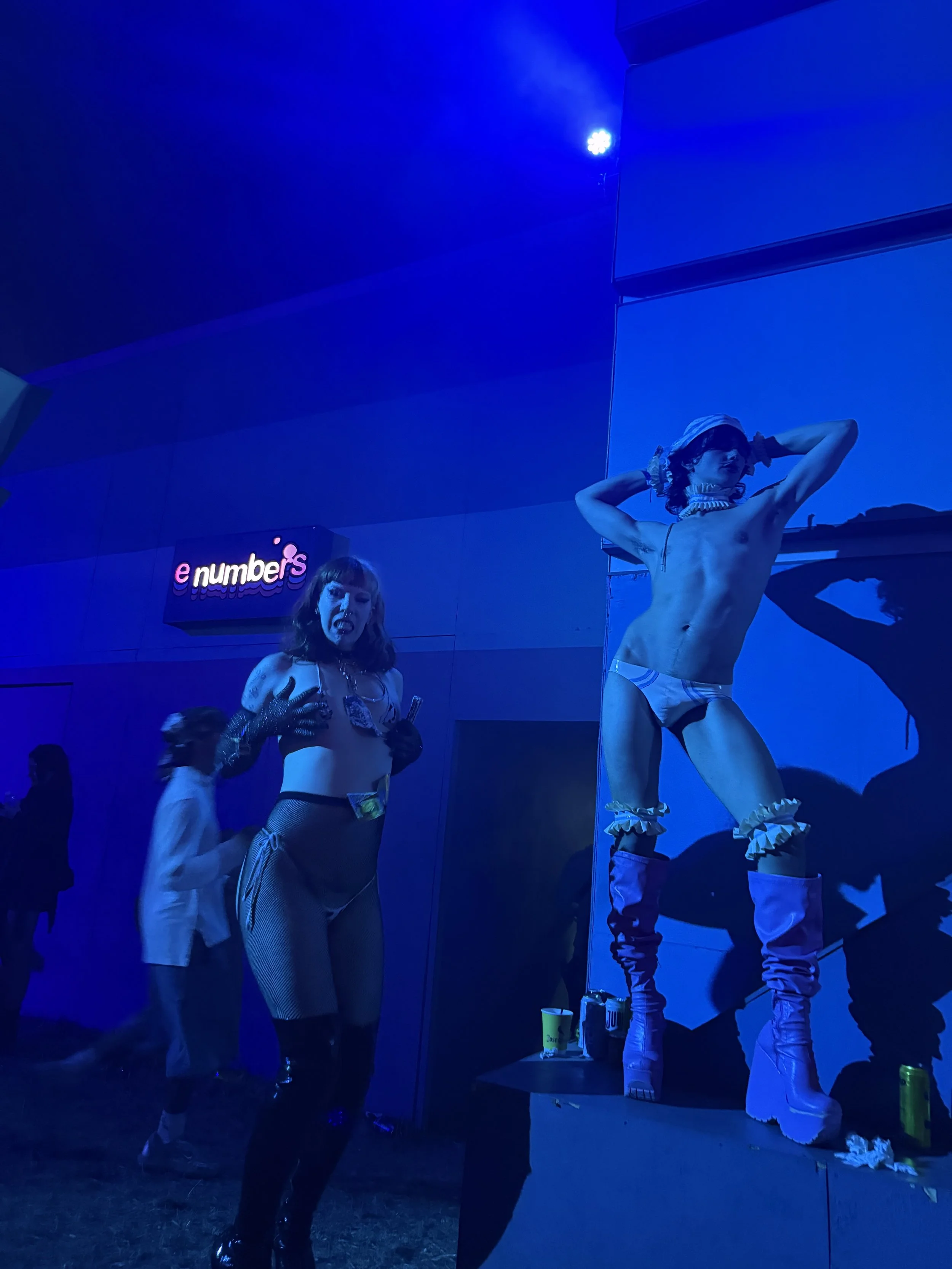 Wilma Hickey Heel in white and blue sailor latex ensemble at Boomtown 2025. [armbands available in shop].