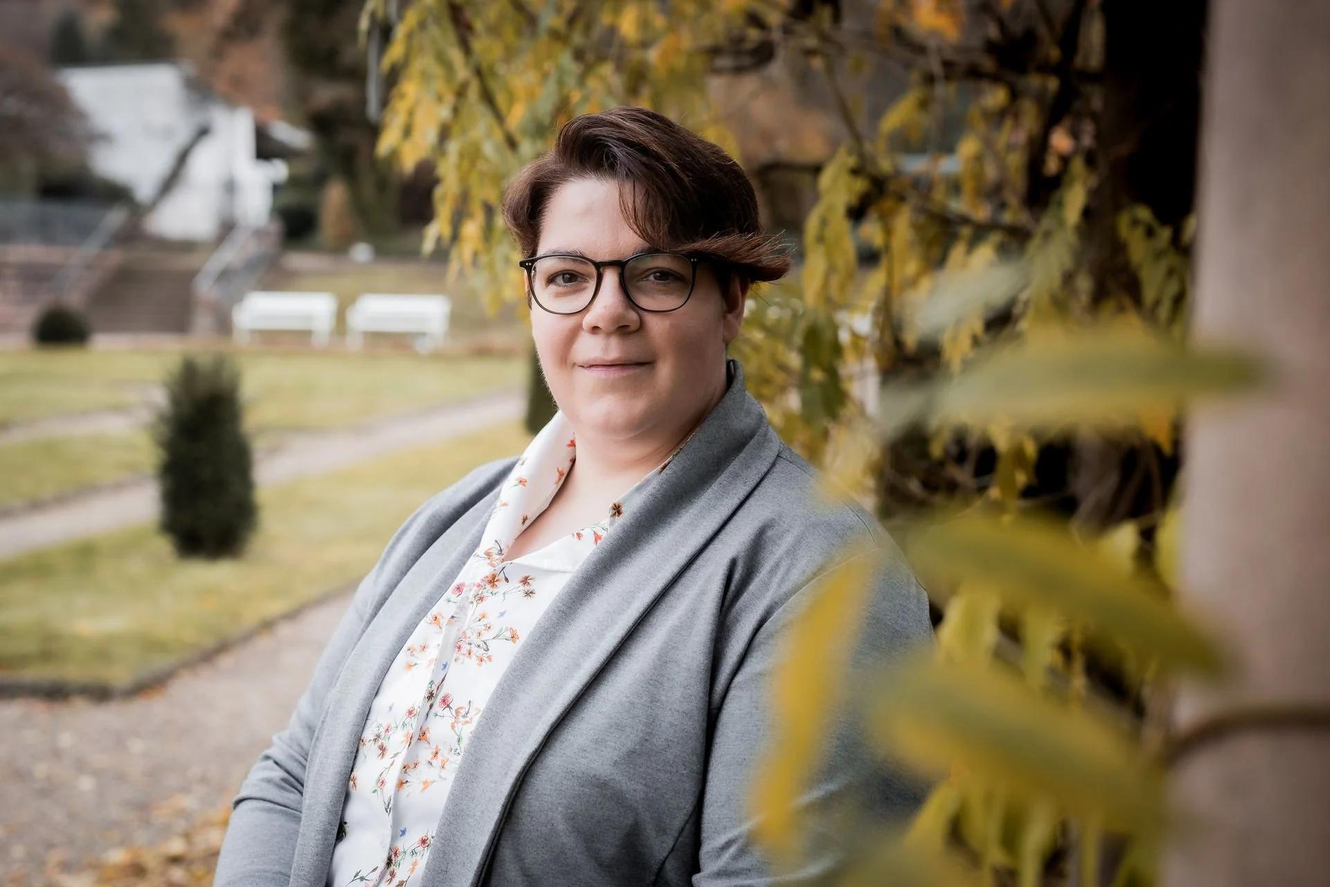 Dr. Kathrin Scheffler in ruhiger herbstlicher Parkumgebung – symbolische Darstellung von Achtsamkeit, Präsenz und Ressourcenorientierung im Somatic Experiencing® und systemischen Coaching.