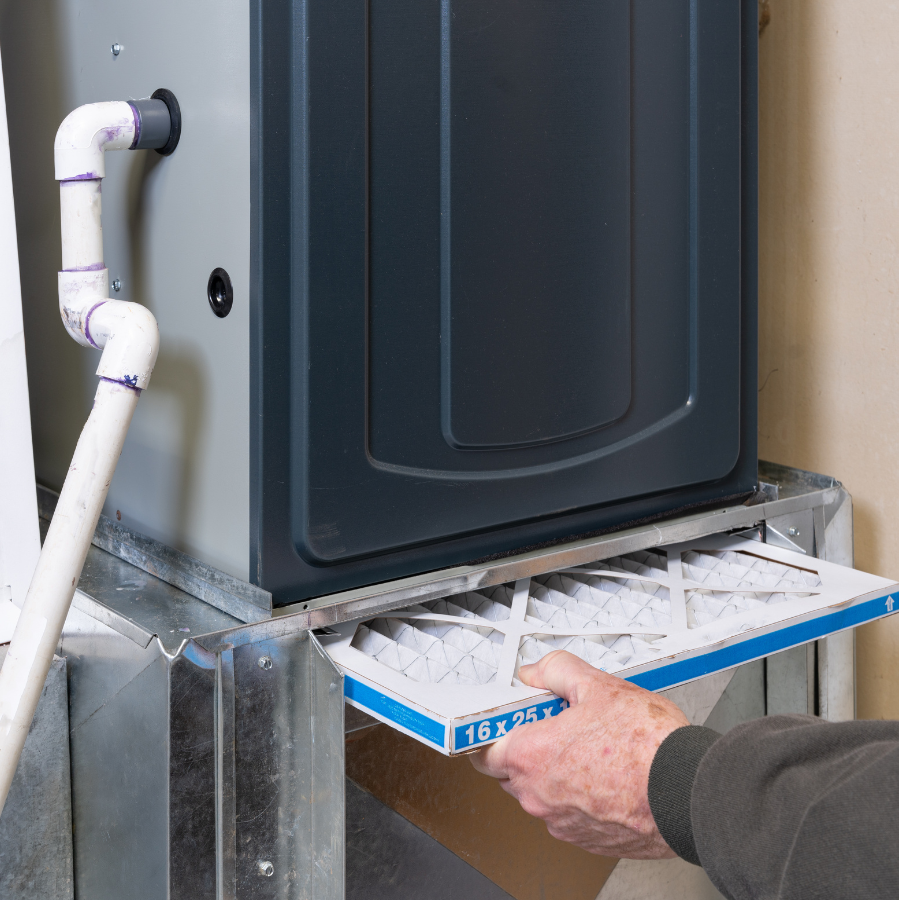 Person inserting a filter into an HVAC or furnace unit.