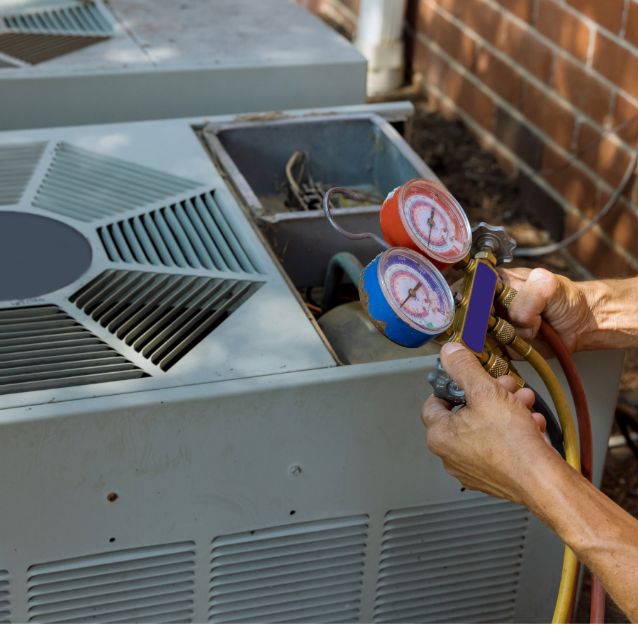A person measuring refrigerant pressure with a manifold gauge set on an air conditioning unit outside.