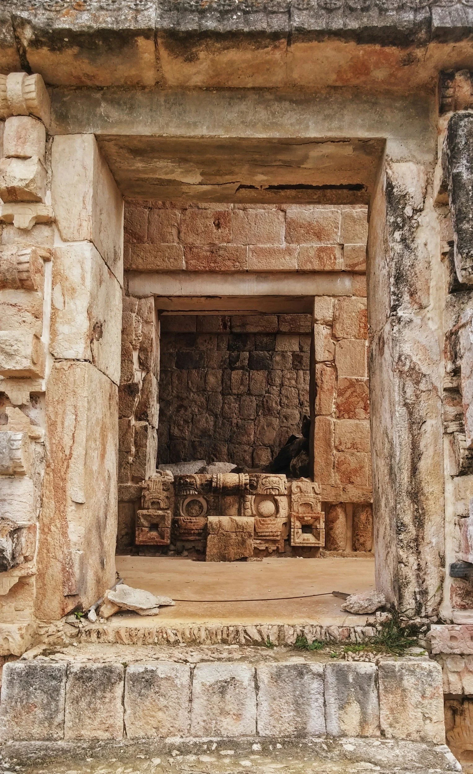 An ancient stone structure with multiple doorways, revealing a small, ornate stone platform inside, possibly part of a historical archaeological site.