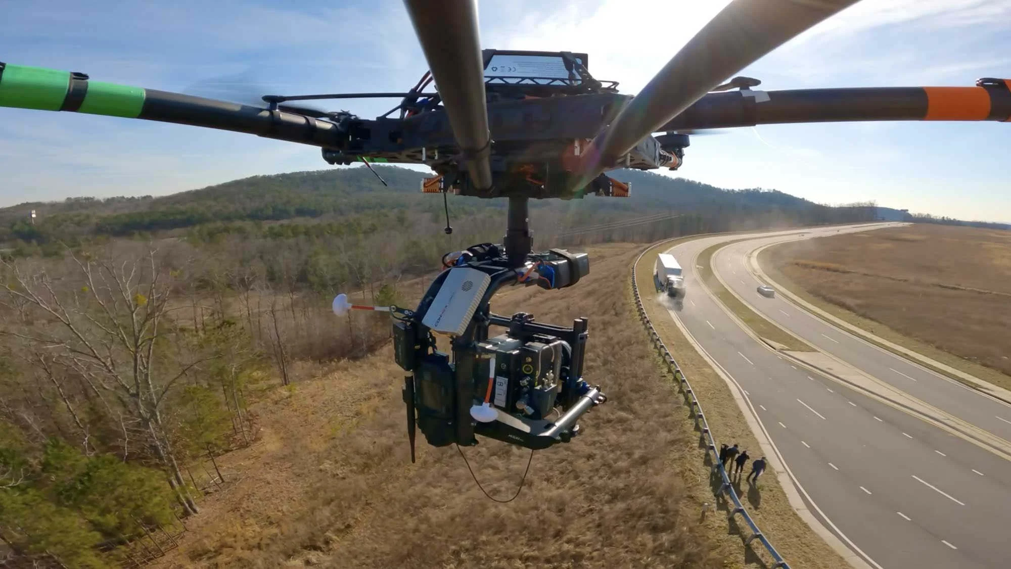 Drone flying above a highway with cars and trucks, capturing footage of the road and surrounding landscape.