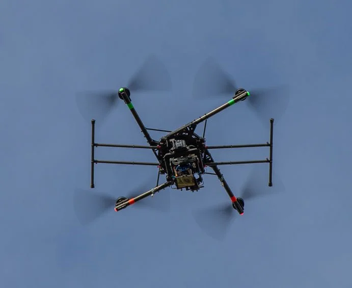 Close-up of a drone with four propellers flying in a clear sky.