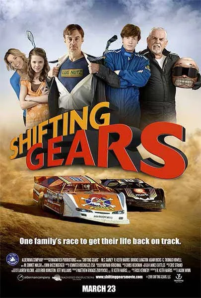 A movie poster for 'Shifting Gears' featuring five characters standing behind race cars on a dirt track, with a cloudy sky in the background. The characters include a woman, two children, a man with a name tag that says 'Ugg Nutz,' and an older man h