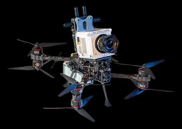 A quadcopter drone with a mounted camera on a black background.