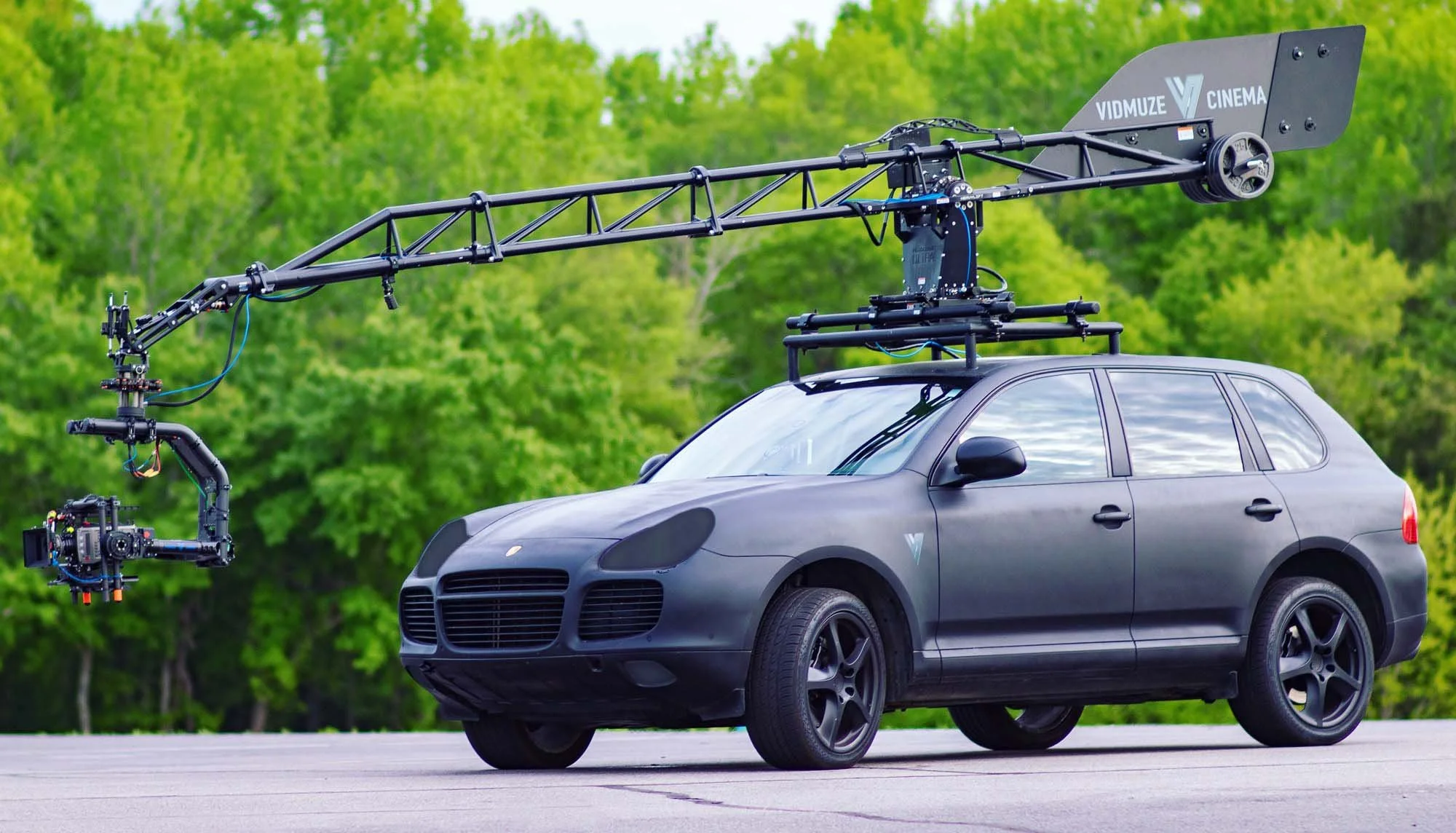 A black matte car with a large camera rig mounted on top, including a camera attached to a robotic arm for filming.