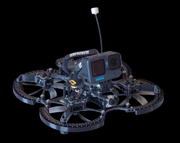 A drone with a camera mounted on top, featuring a carbon fiber frame and multiple propellers, against a black background.