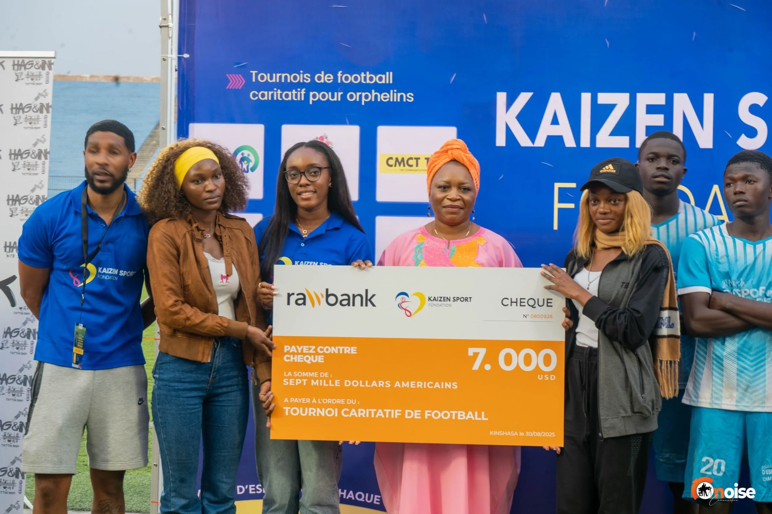 Group of people holding a large donation check at a charity football event