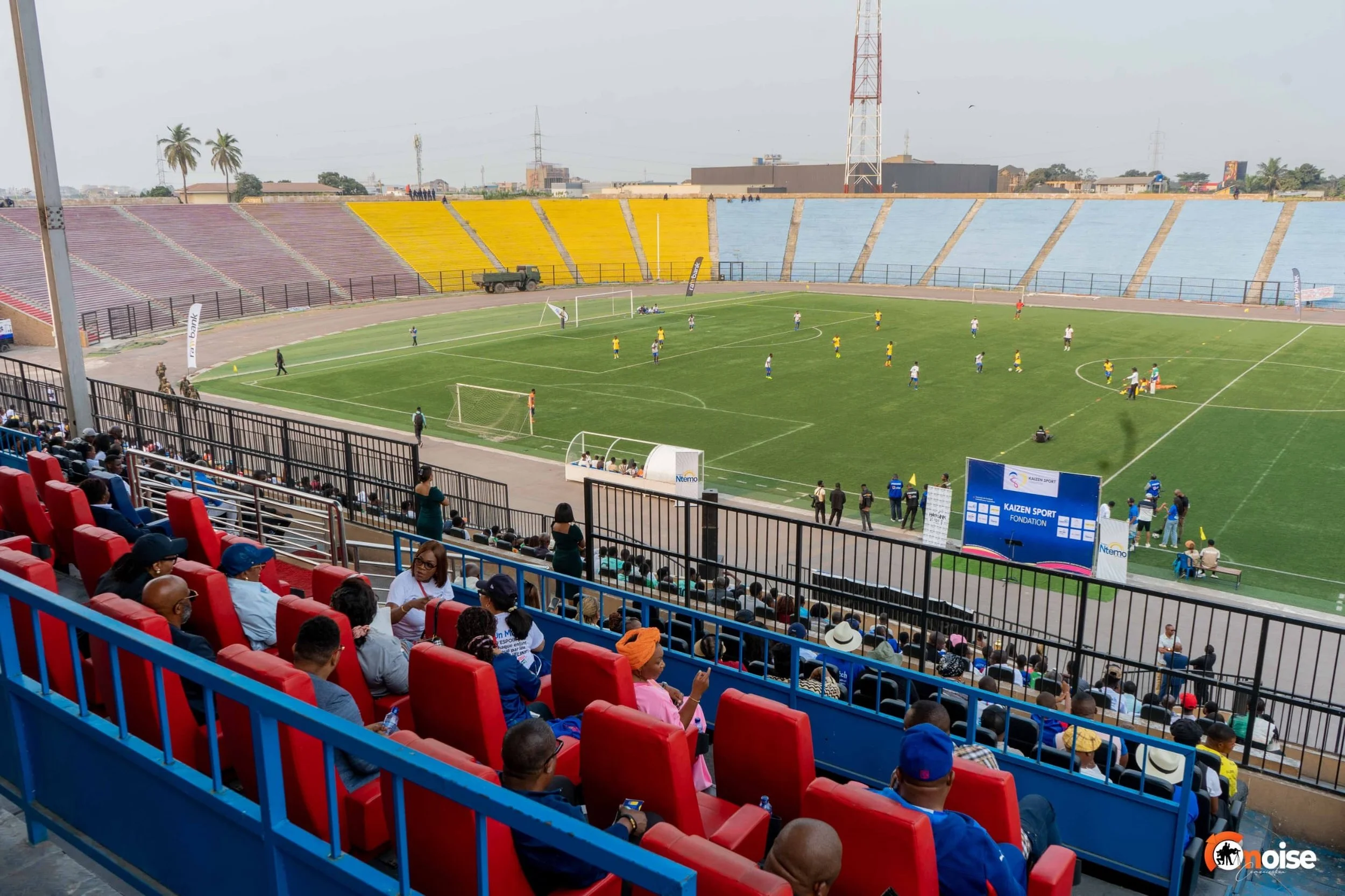 A soccer stadium filled with spectators watching a game on the field, with players actively engaged in the match.
