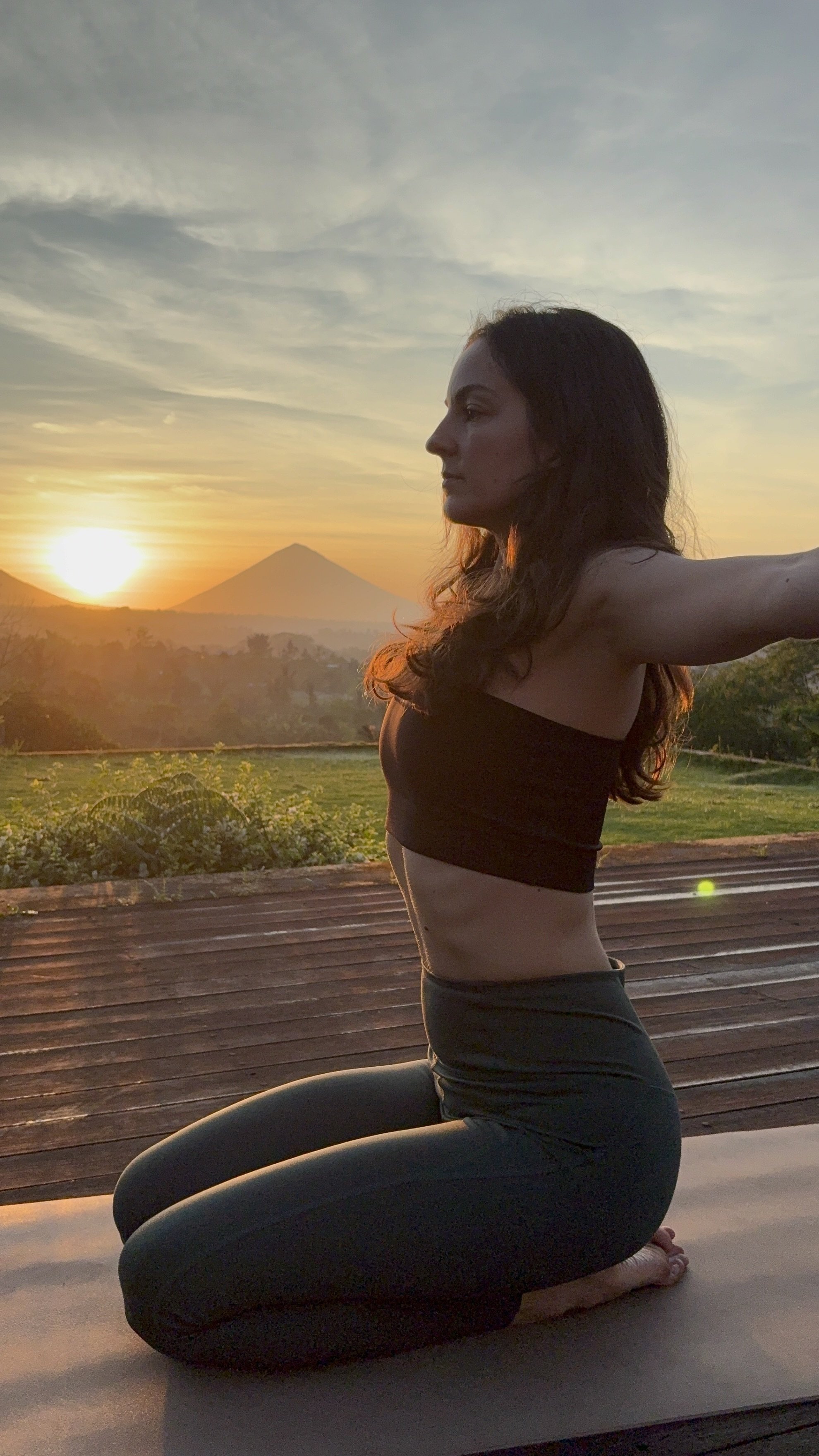 Frau praktiziert Yoga im Sitzen auf einer Holzterrasse im Freien bei Sonnenaufgang mit Blick auf den Mount Fuji.
