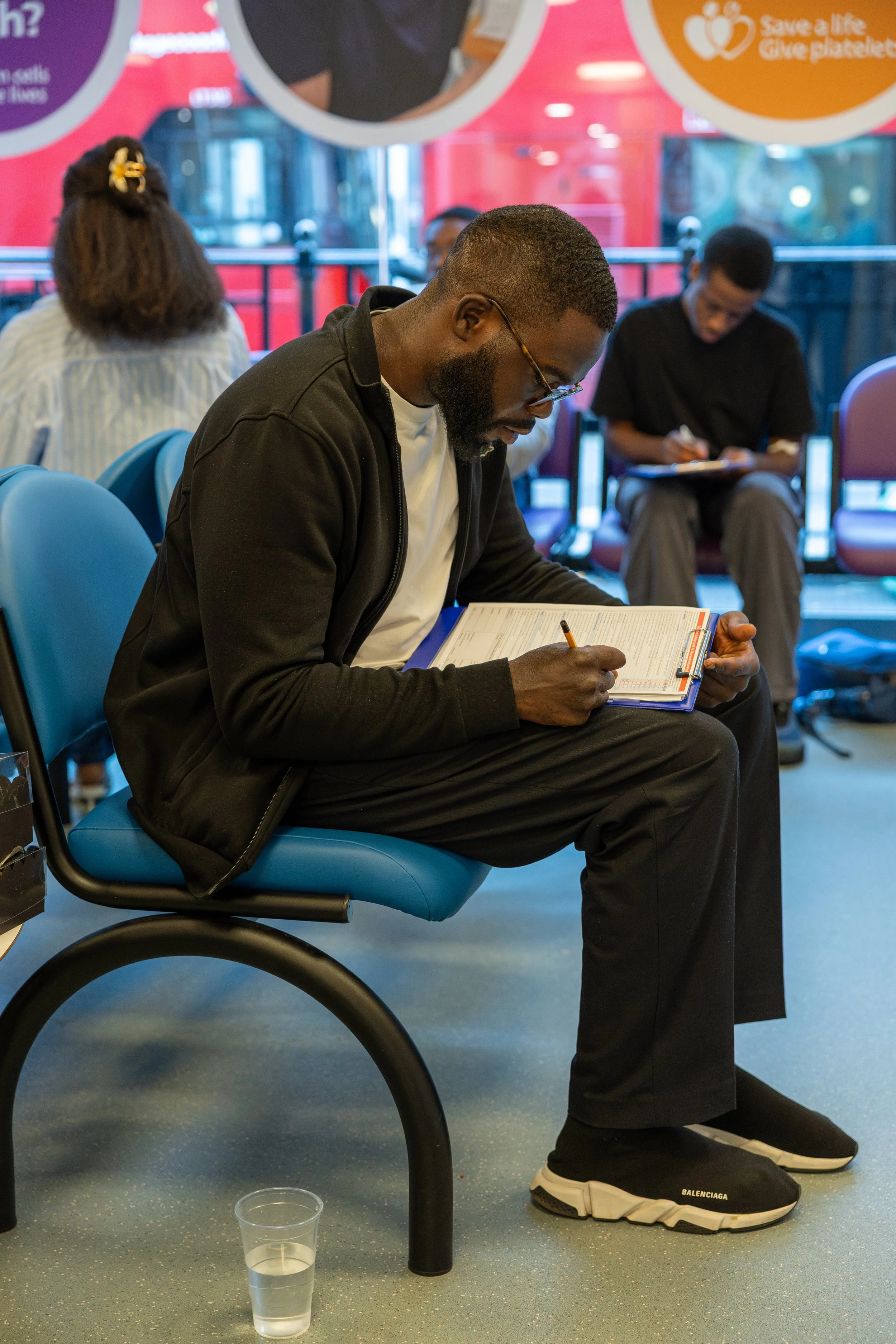 A young Black man filling out a blood donor health form at a Black Blood Matters blood donation event