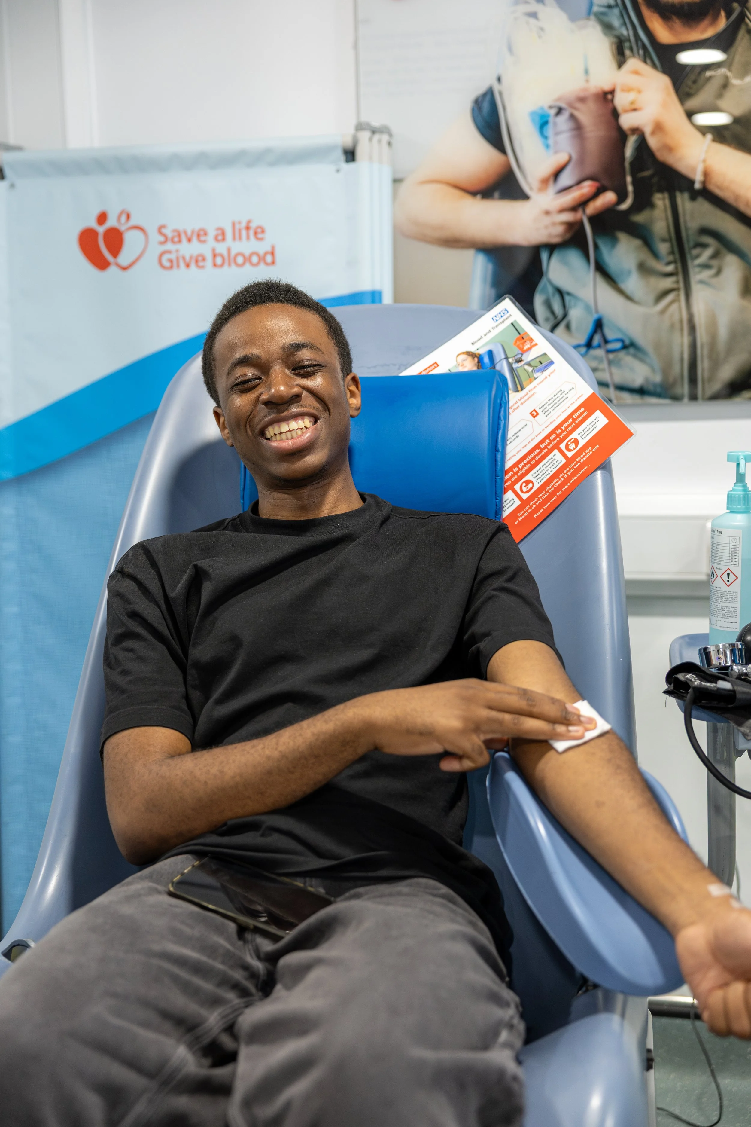 Young Black man donating blood with a big smile on his face at a Black Blood Matters event