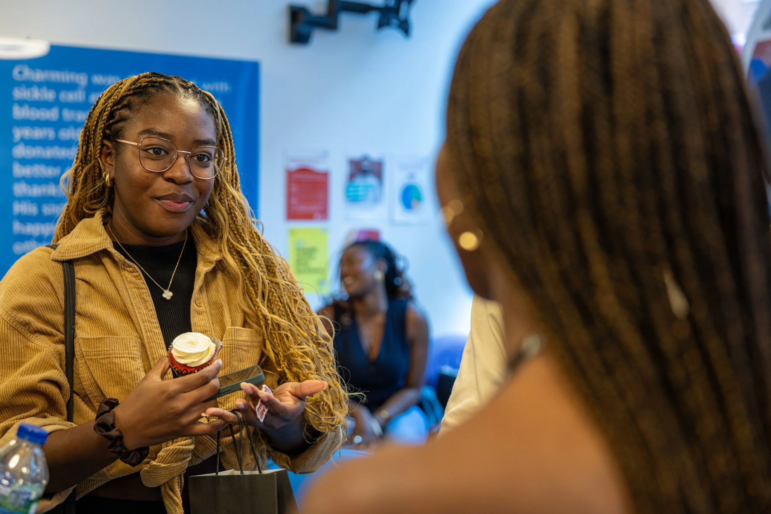 Young Black woman listens as she is educated about blood donation at a Black Blood Matters event