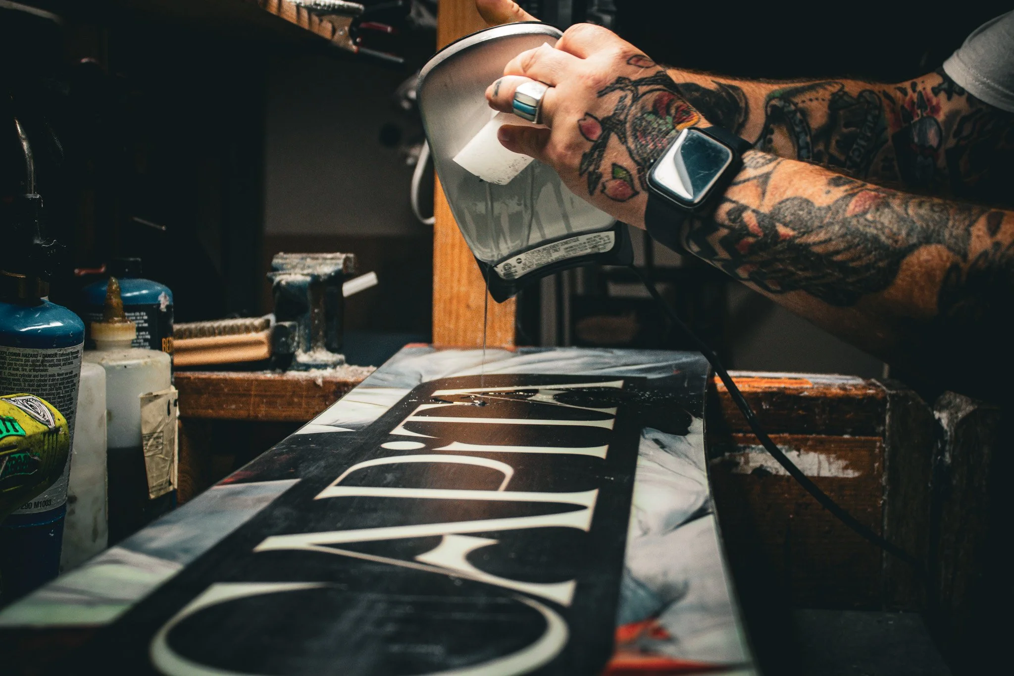 Milo Snow and Skate workshop photograph showing a board being waxed by a tattooed shop worker.