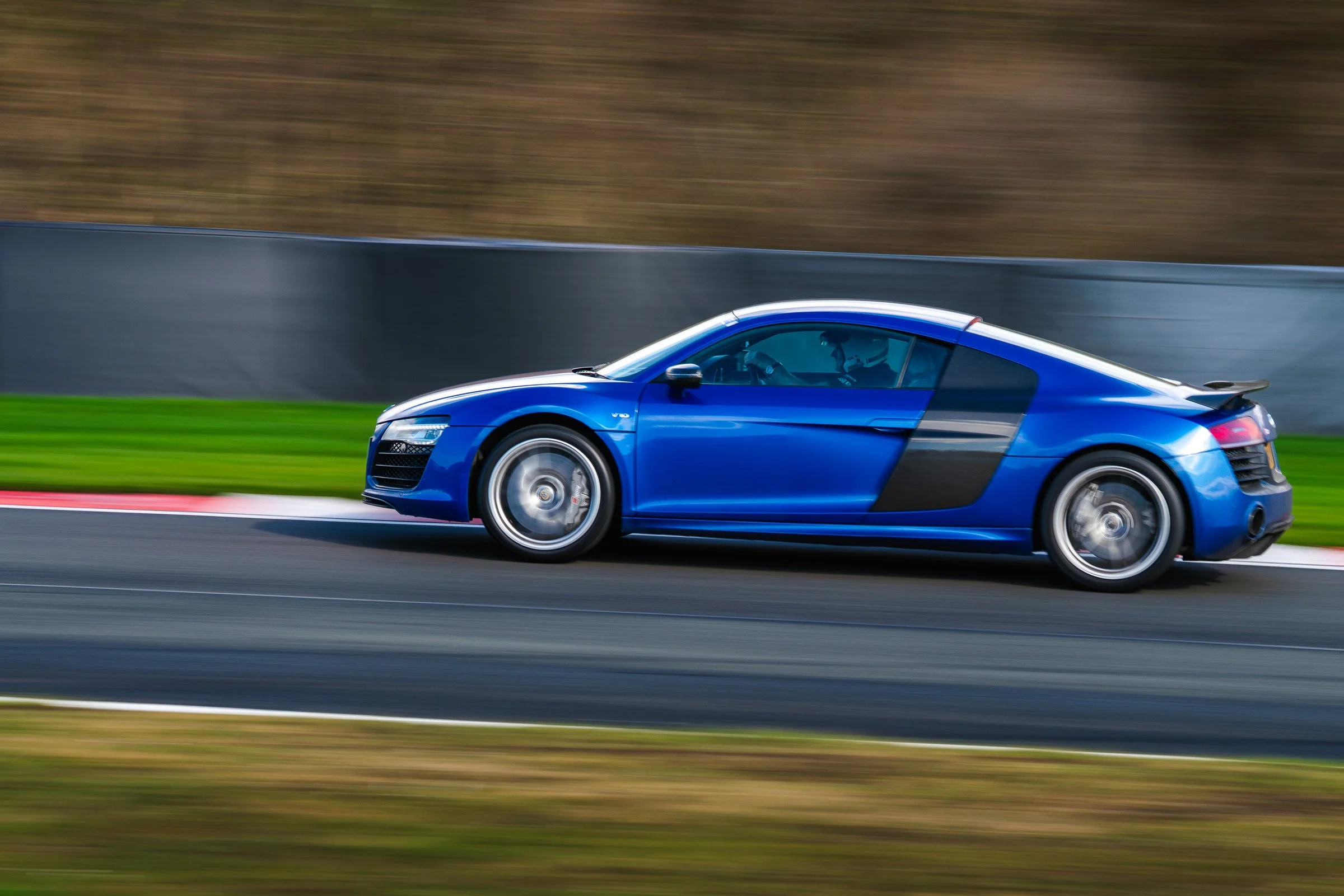 Blue sports car racing on a track with a blurred background.