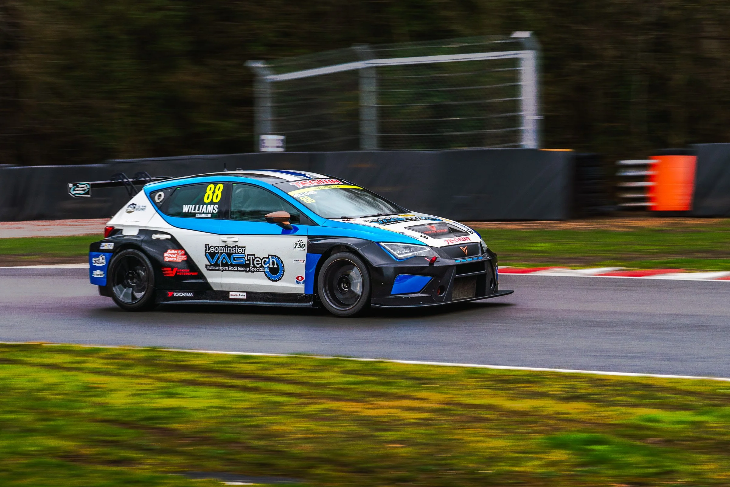 A race car on a track, painted in blue, white, and black with the number 88 on the side, speeding past the camera.