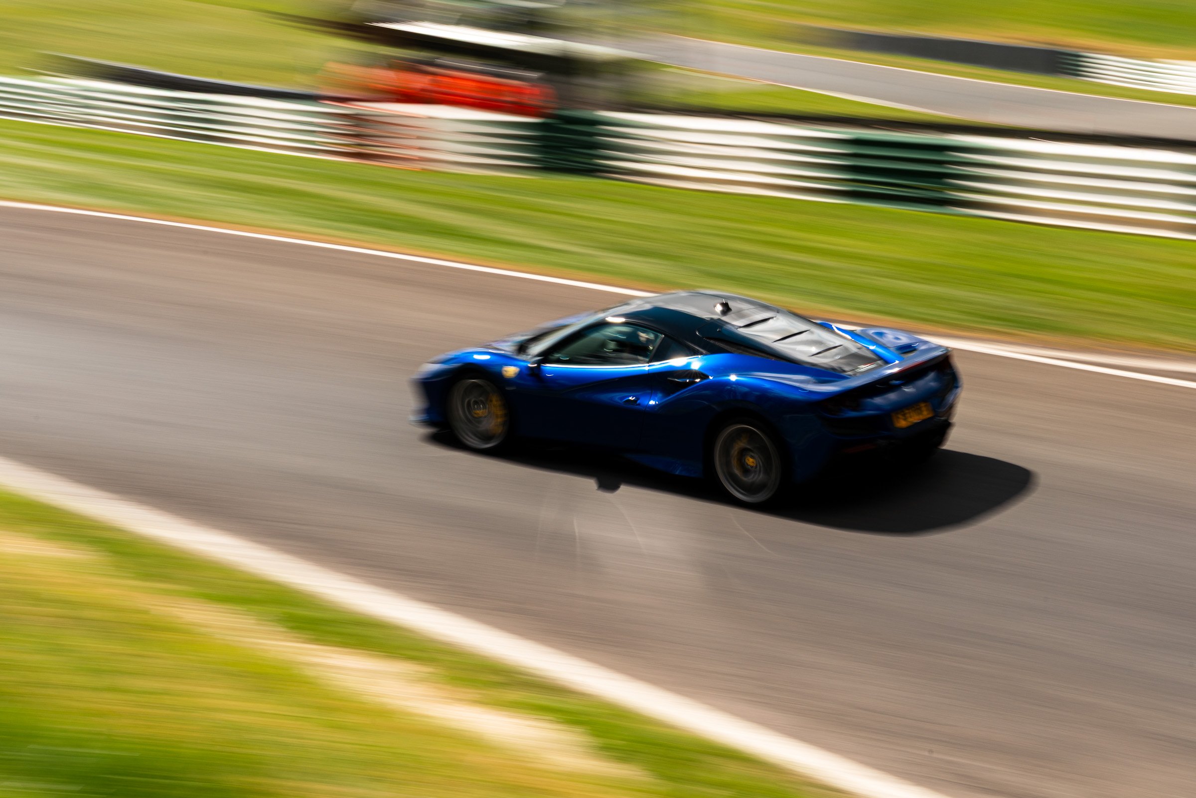 A blue racing car speeding on a race track with blurred background and motion blur effect.