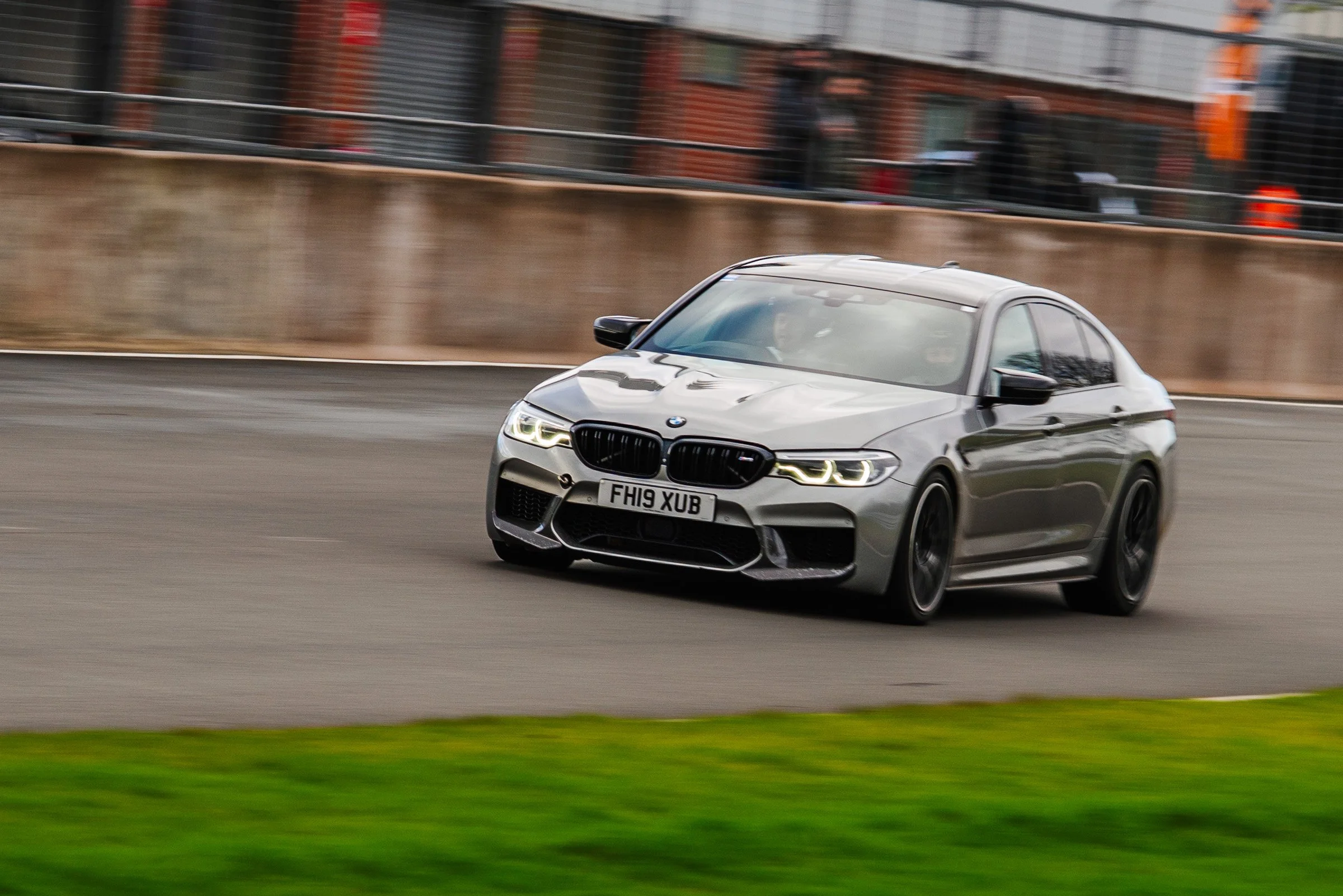 A silver BMW M5 car racing on a track with a blurred background.