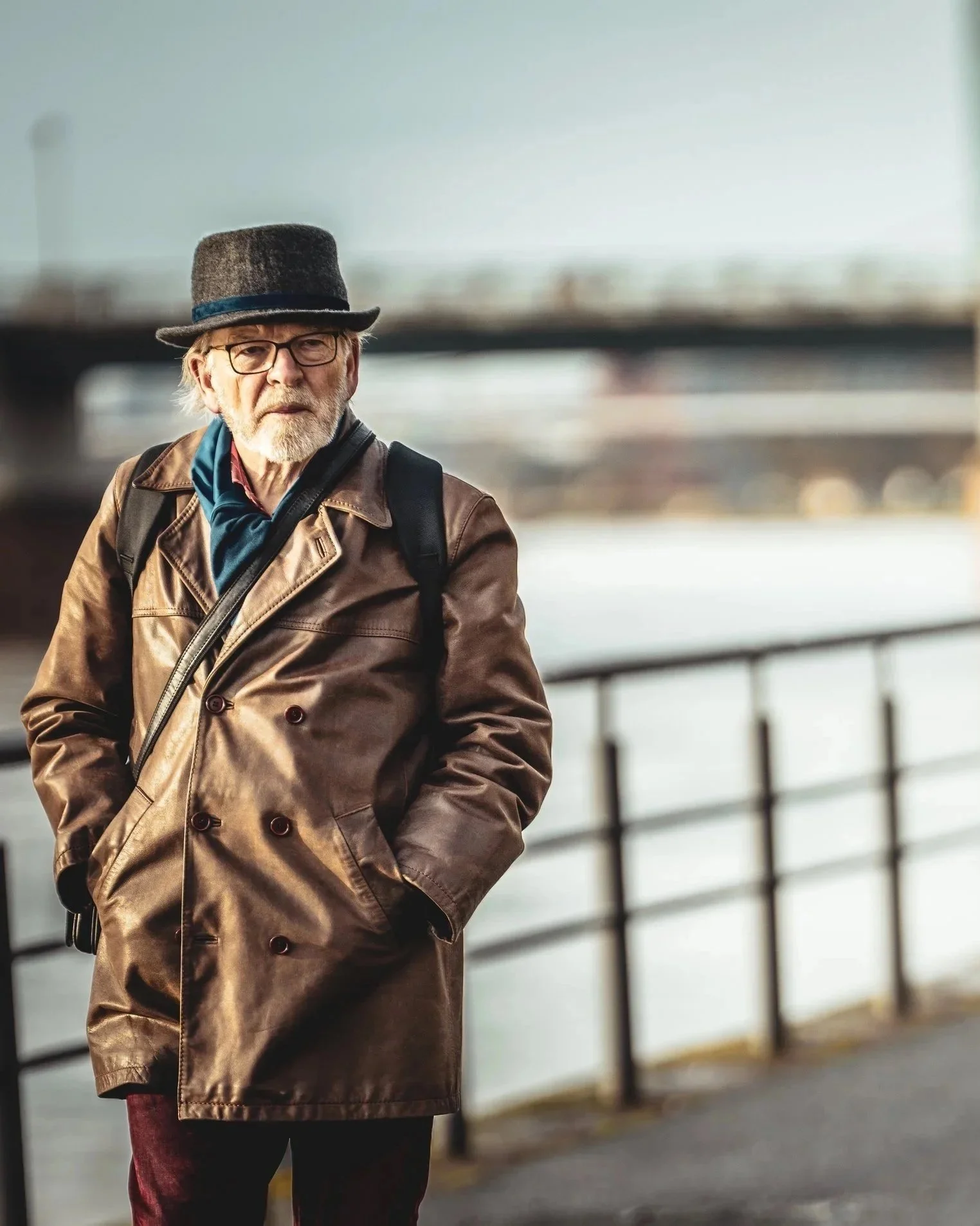 Amid the slow breath of the river, he pauses, hands deep in worn leather, eyes carrying more seasons than the summer allows.
