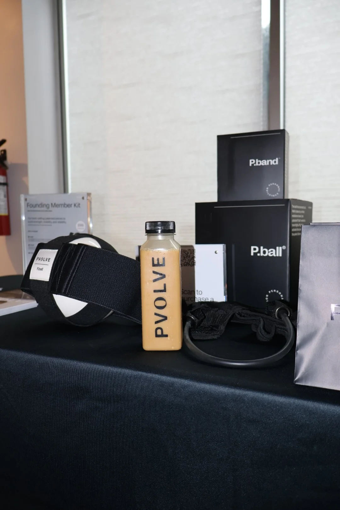 Display of vaping products including a Vaporesso PVOLV E vape, P. Band and P. Ball boxes, a black and white device, and a bottle labeled PVOLVE on a black table with a window in the background.
