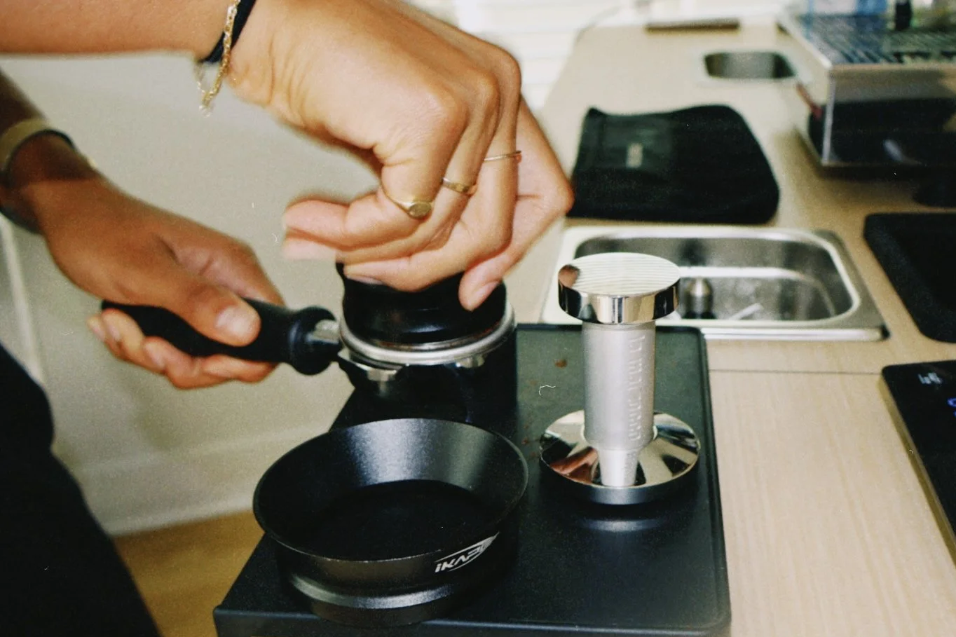 Person using a pestle and mortar on a kitchen countertop, with a coffee tamper in the background.