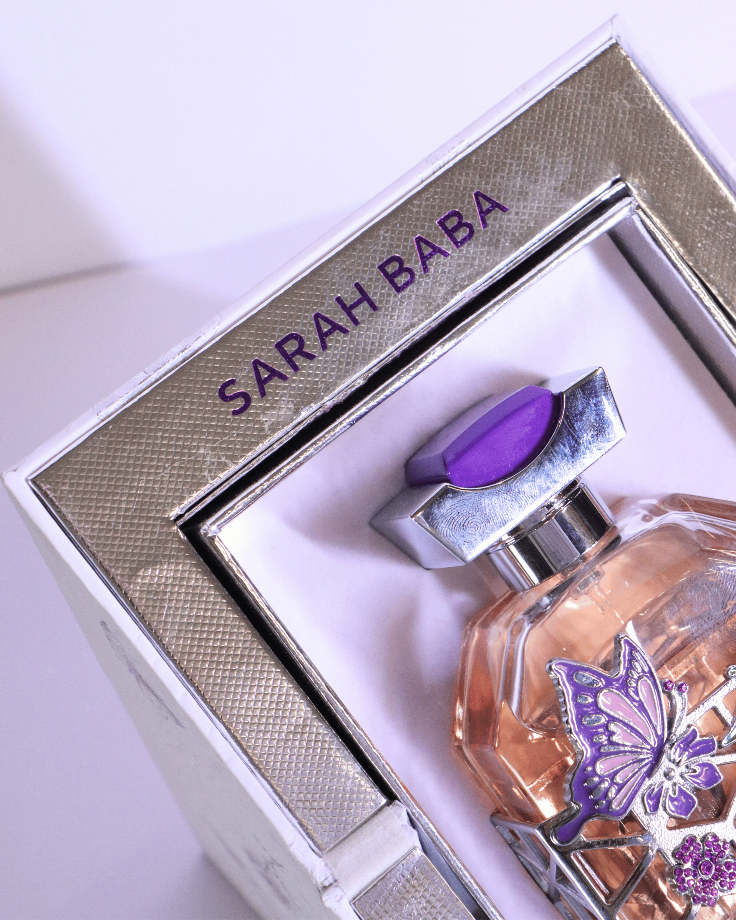 Papillion Violet a perfume bottle with a purple butterfly design inside a shiny silver box with a purple label