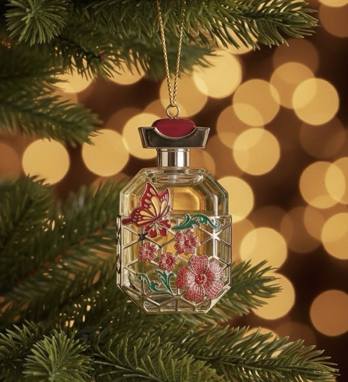 Decorative perfume bottle hanging from the Christmas tree with blurred warm yellow lights in the background.