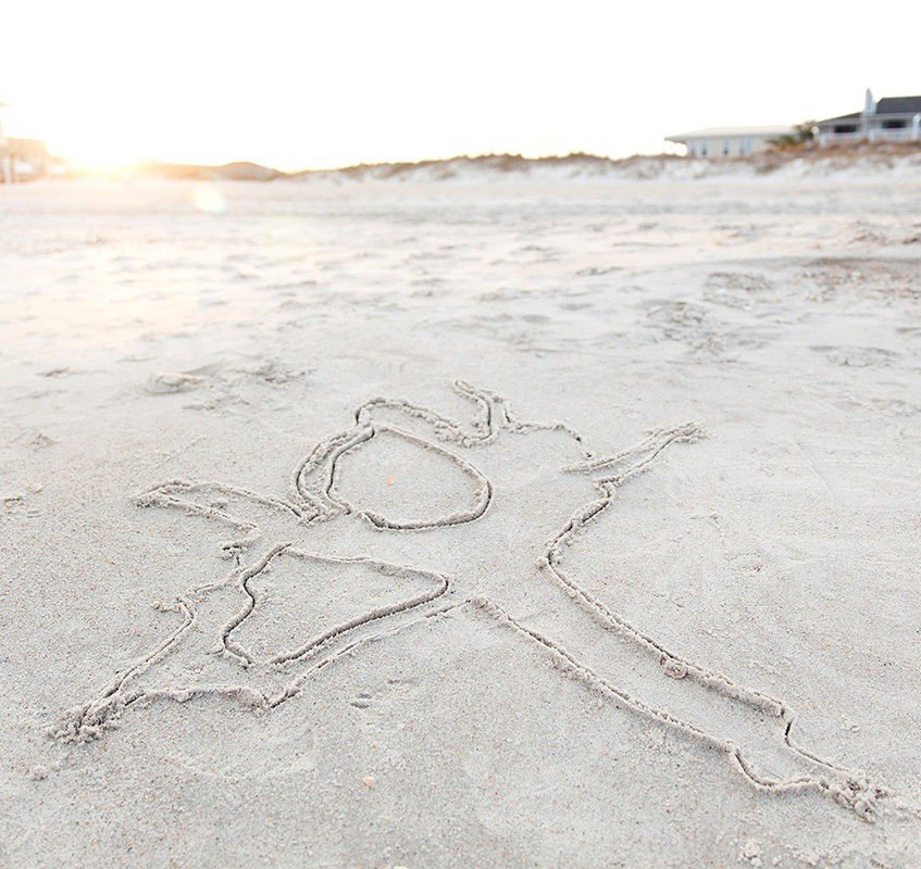 A starfish drawn in the sand at the beach during sunset.