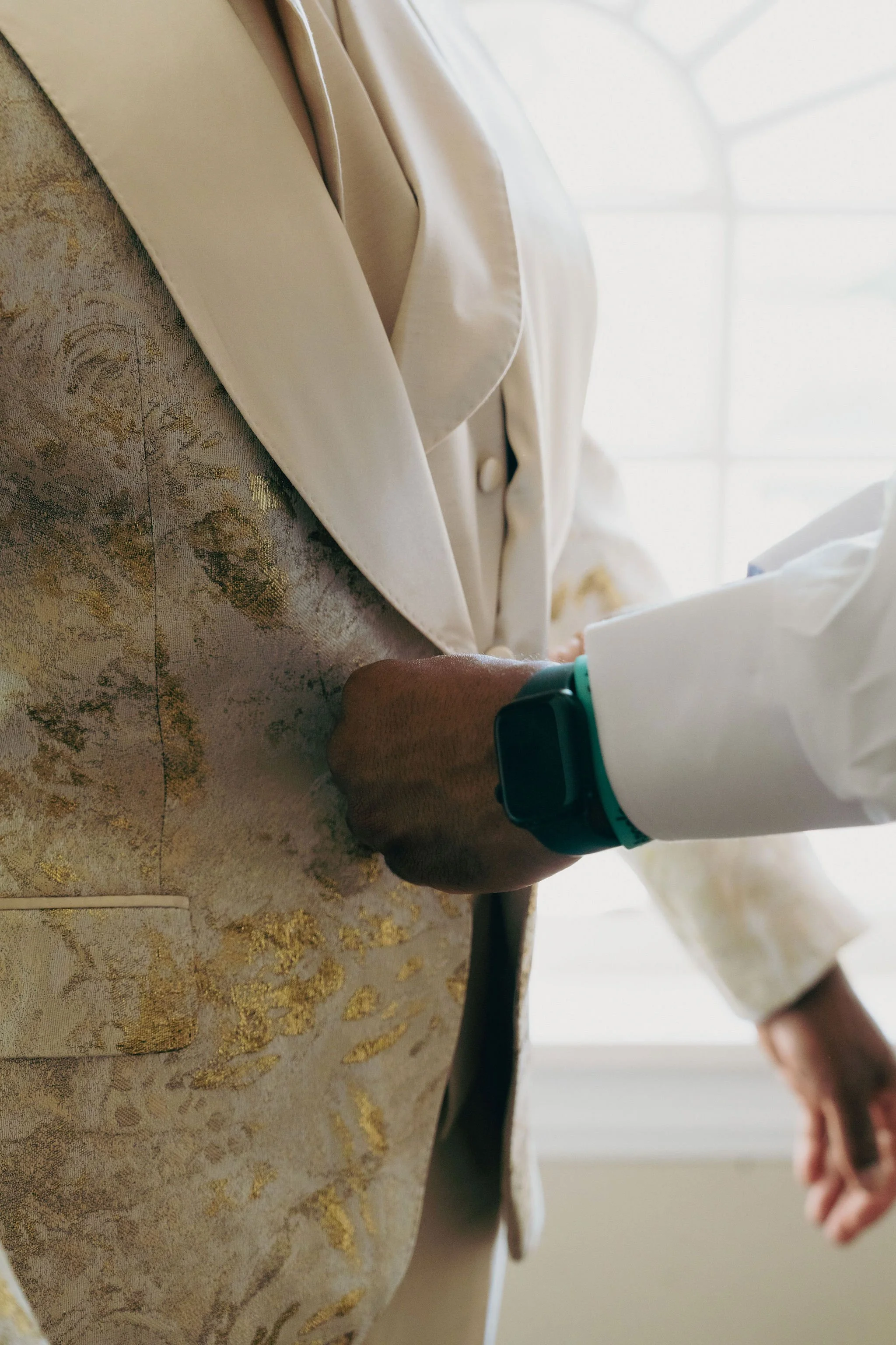A man wearing sunglasses, a white shirt, and a black bow tie opening his suit jacket to reveal a lining with a collage of pictures.