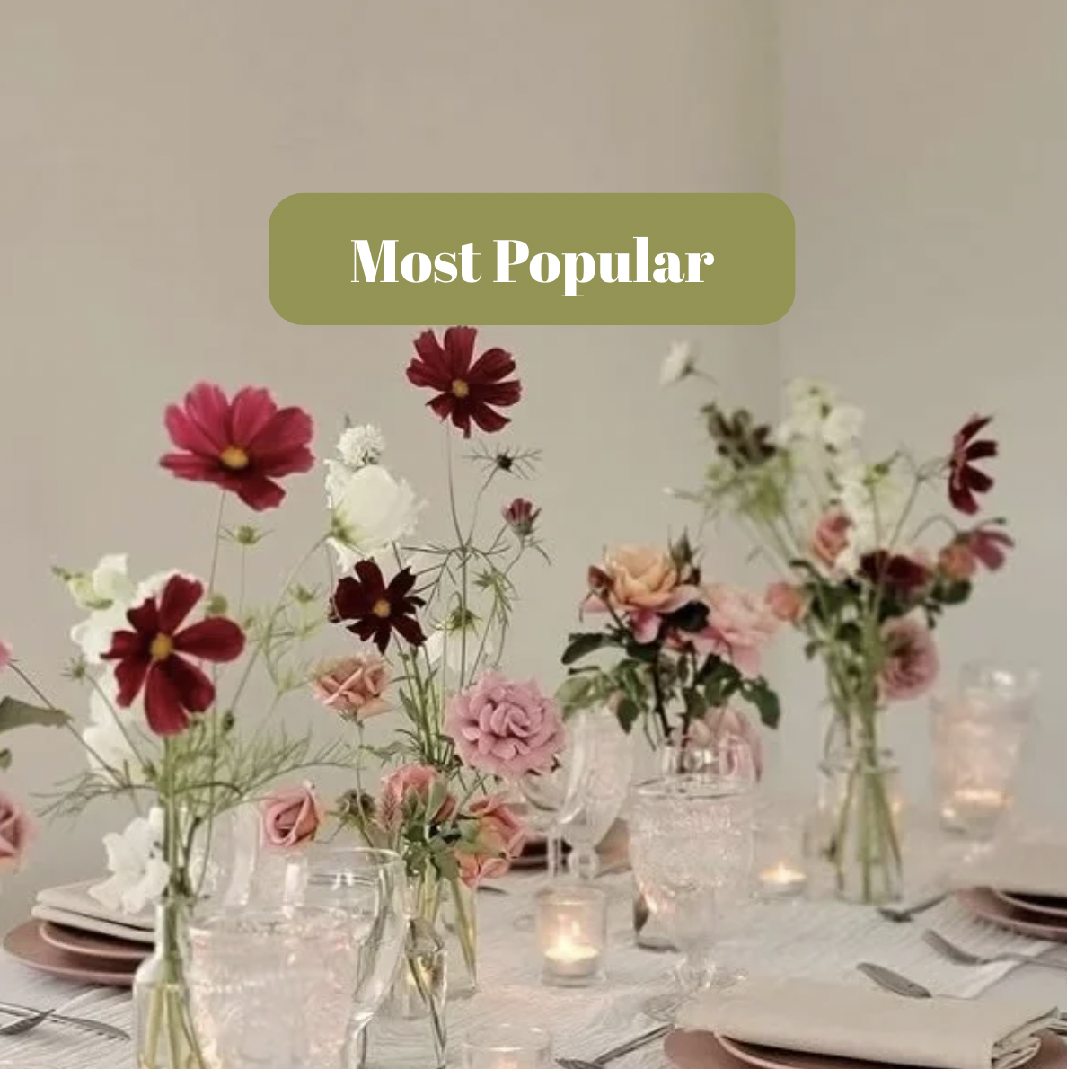 Elegant table setting decorated with pink and white flowers in vases, candles, plates, napkins, and silverware.