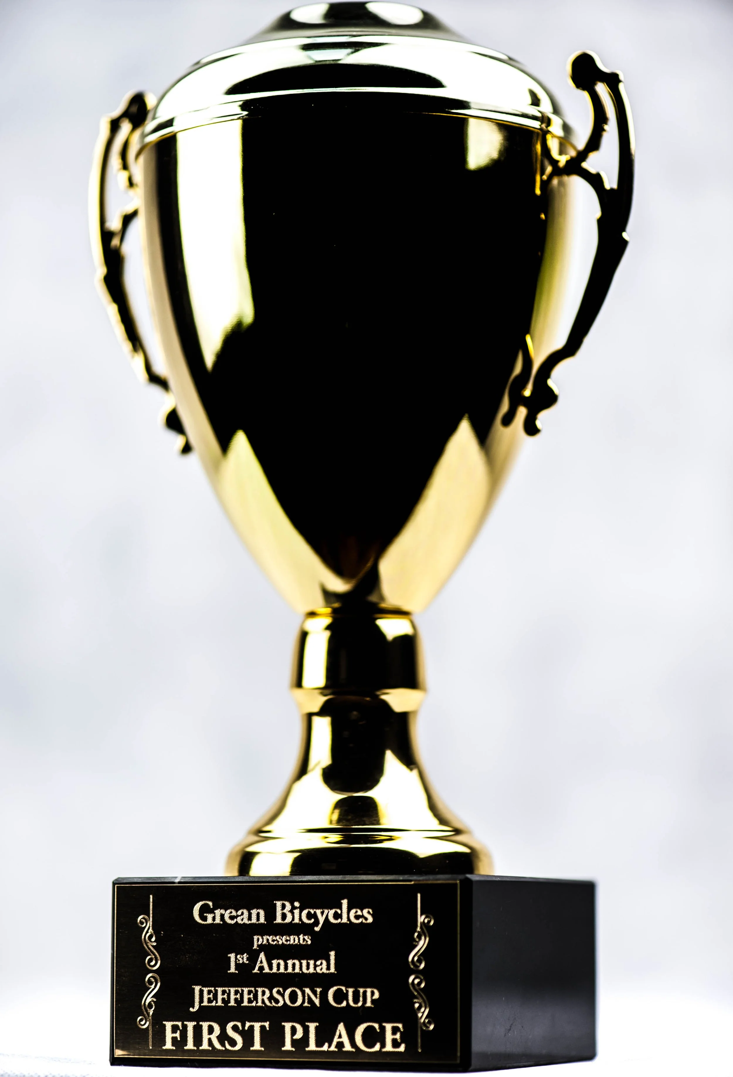 Gold trophy cup with black plaque reading 'Grein Bicycles presents 1st Annual Jefferson Cup First Place'.