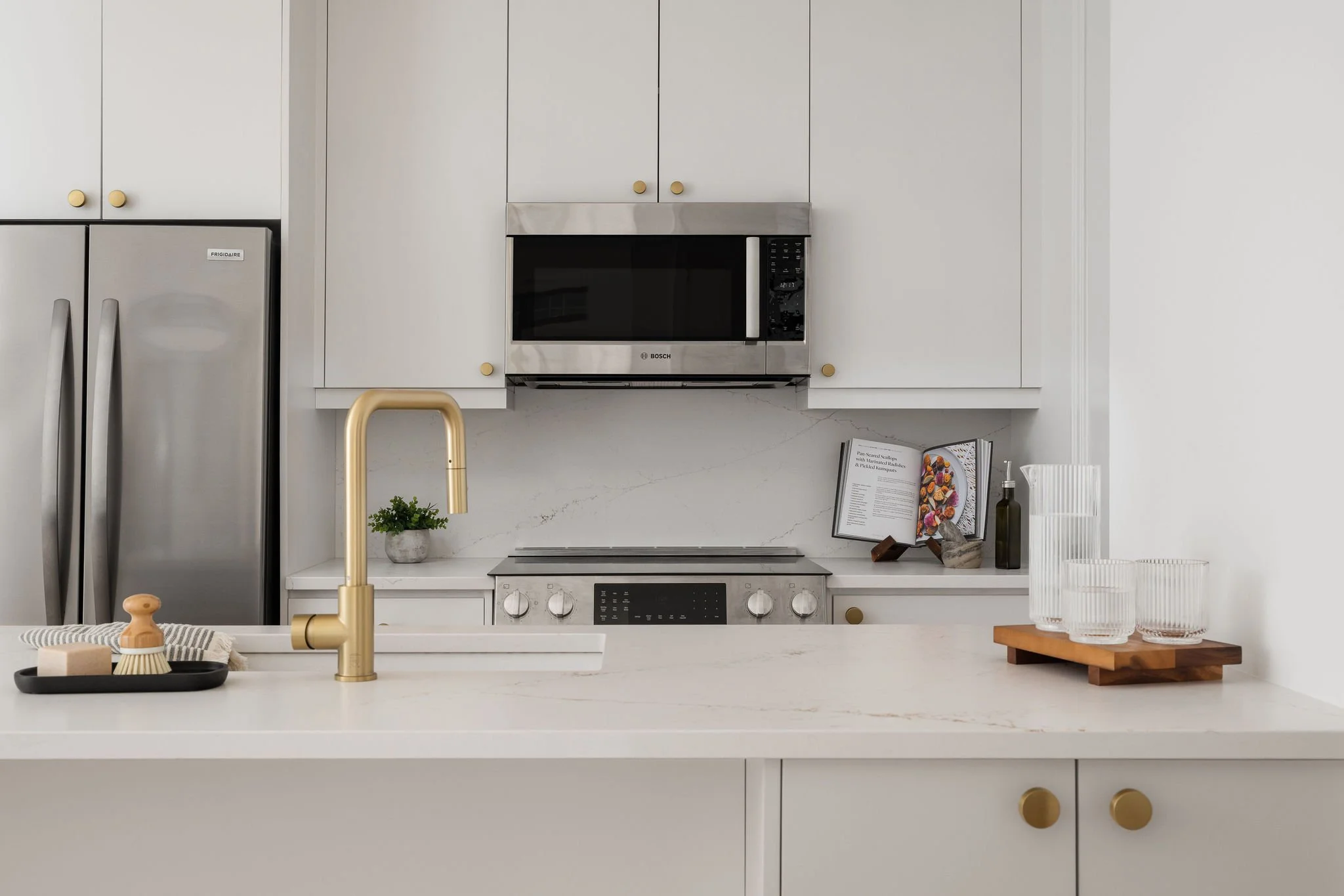 White Kitchen with Gold Fixtures & Waterfall Island Countertop