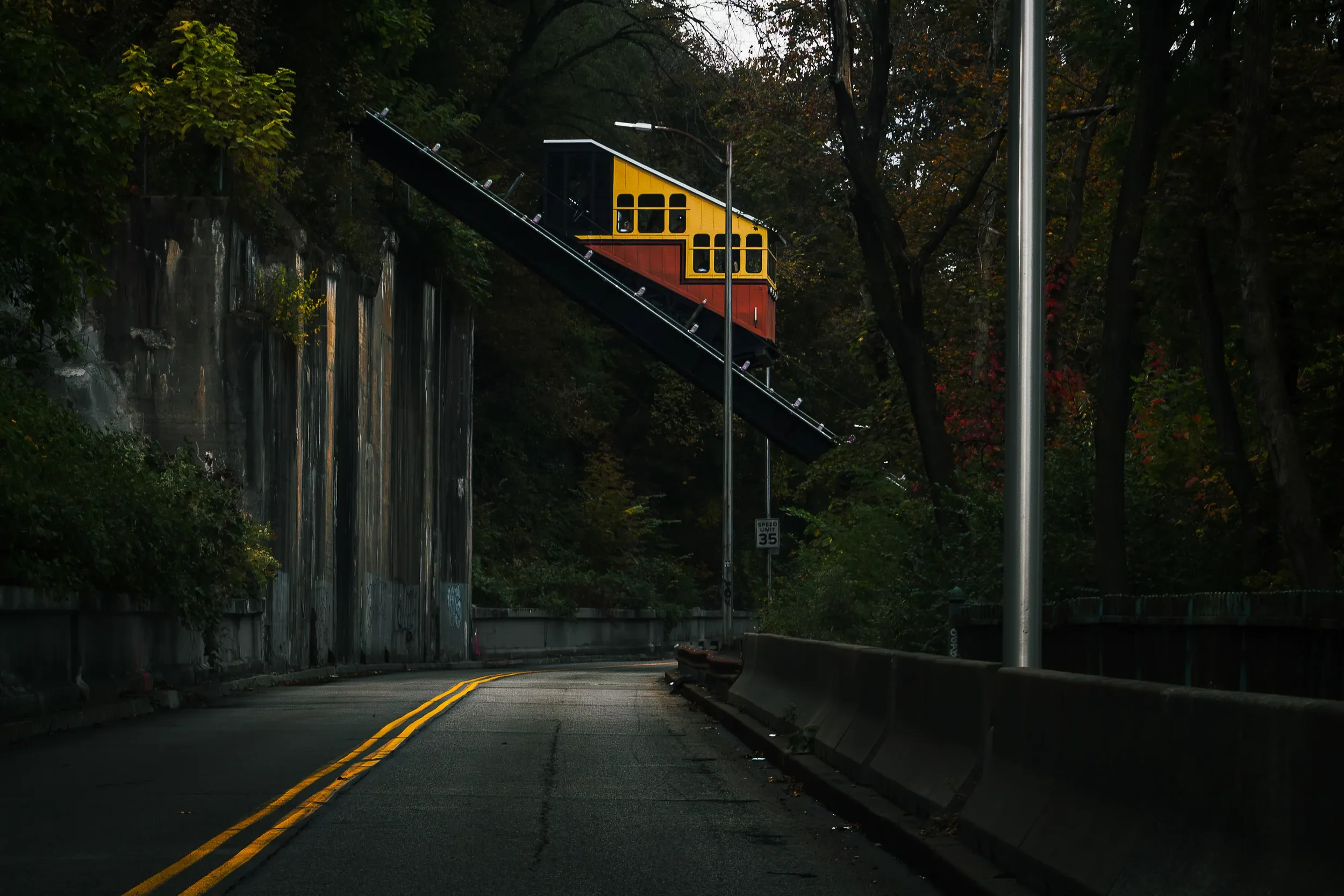 A yellow gondola going up an incline over a road in Pittsburgh, PA